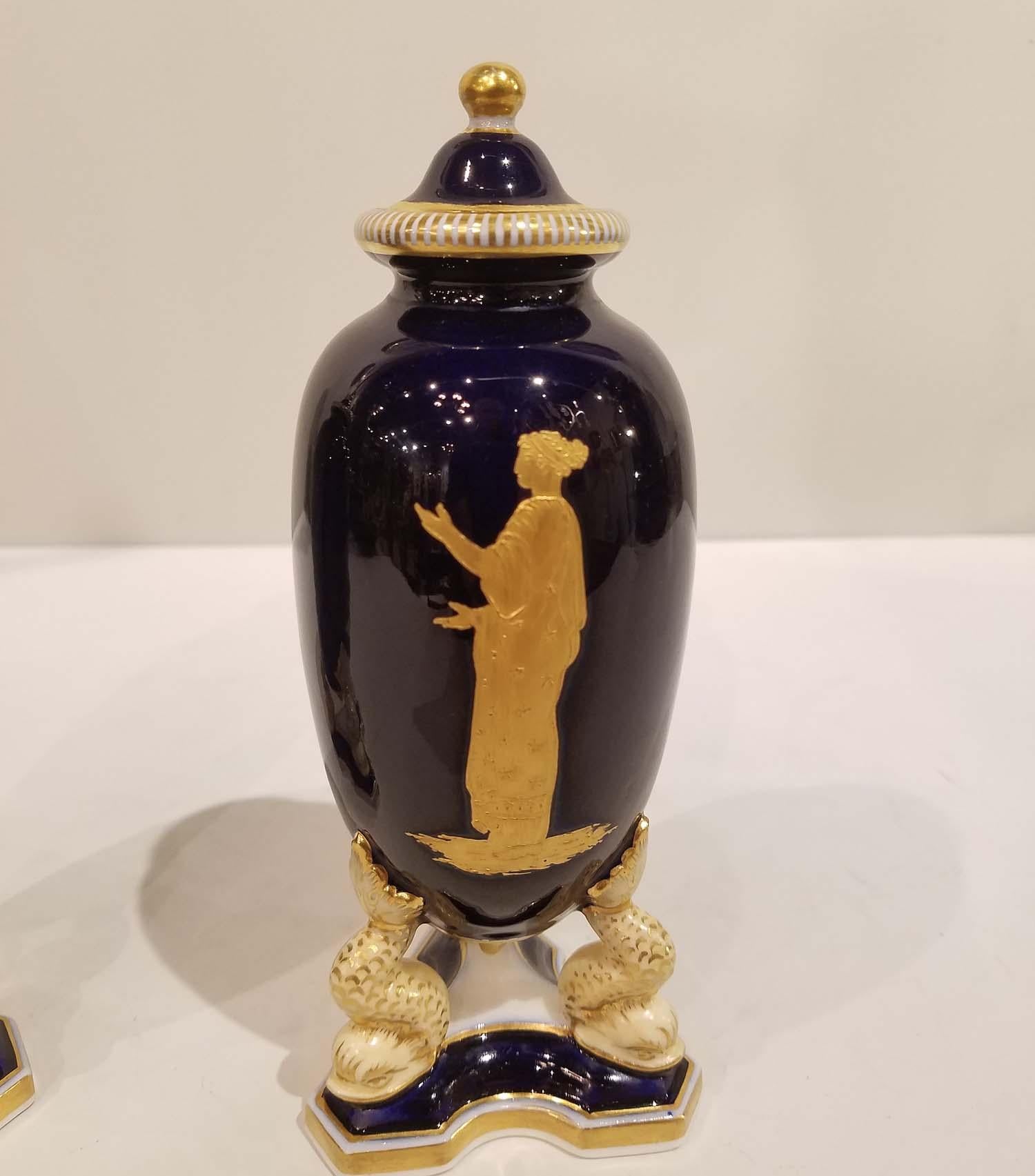 This Pair of Grainger & Co. Worcester covered vases are in rich cobalt blue color with gold decoration of neoclassical figures and dolphin legs on a triangular bases, circa 1890. Made in England,