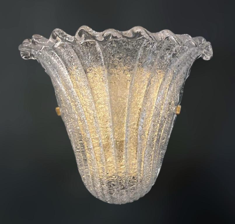 Italian wall light with a Murano glass shield hand blown in Graniglia technique to produce granular textured effect, mounted on gold plated finish frame / Made in Italy 1960s, in the style of Barovier e Toso
Measures: Height 9.5 inches, width 12
