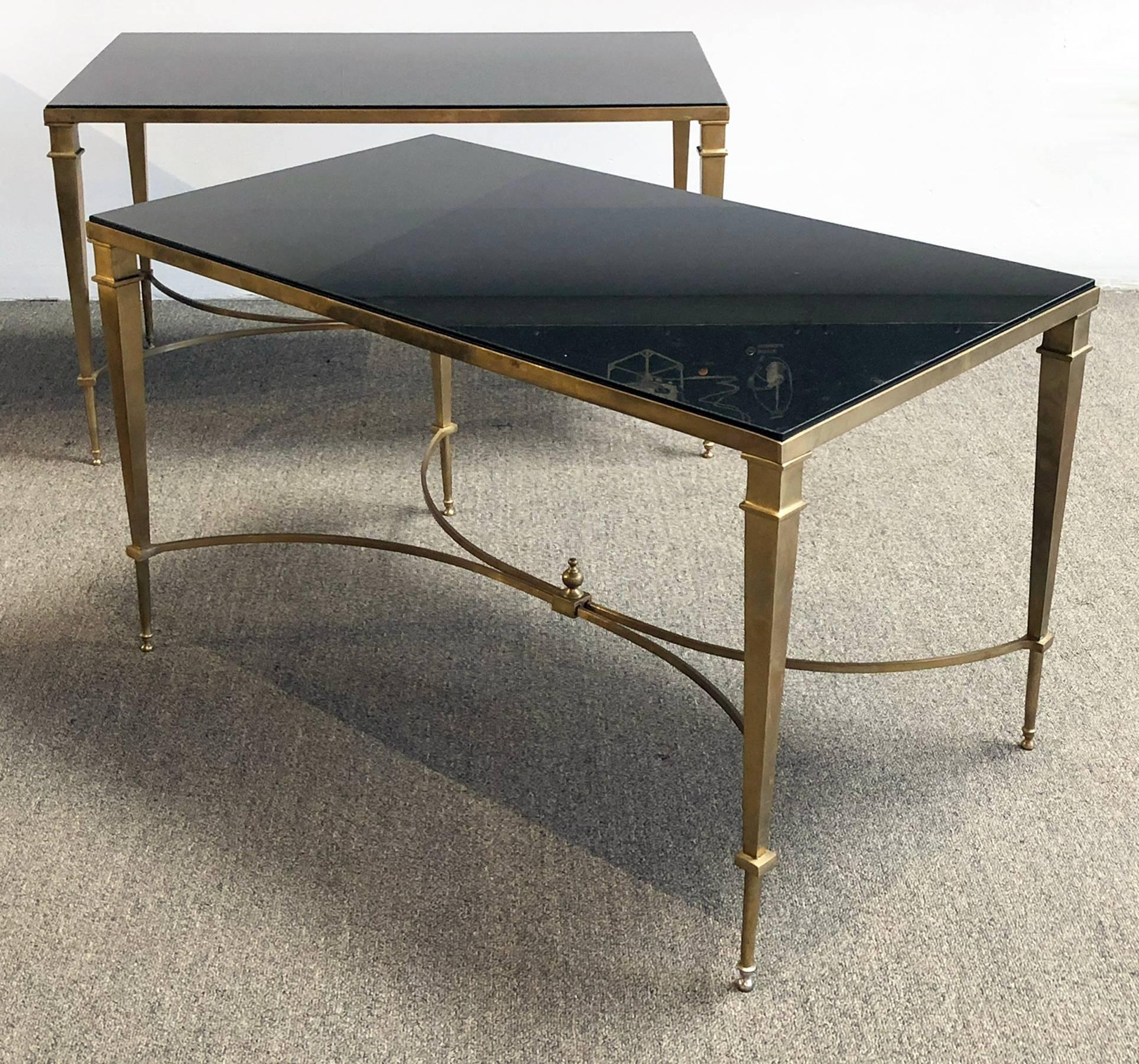 Pair of neoclassical revival tables. Price is for both. Features polished black granite tops with brass frames. The brass finish has a slightly patinated look.