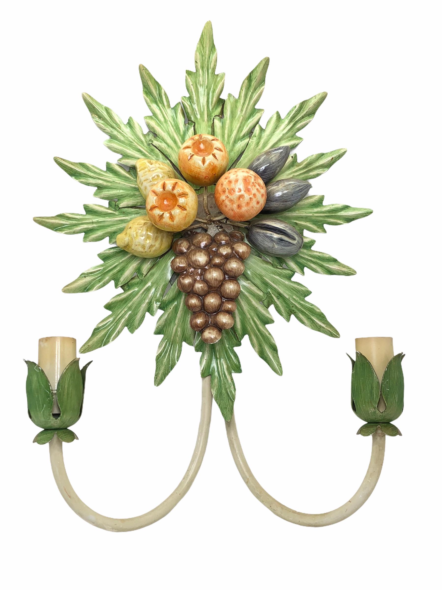 A pair Hollywood Regency midcentury grape, fruits and leaf florentine sconces, each fixture requires two European E14 candelabra bulbs, each up to 40 watts. The wall lights have a beautiful patina and give each room an eclectic statement. Found at