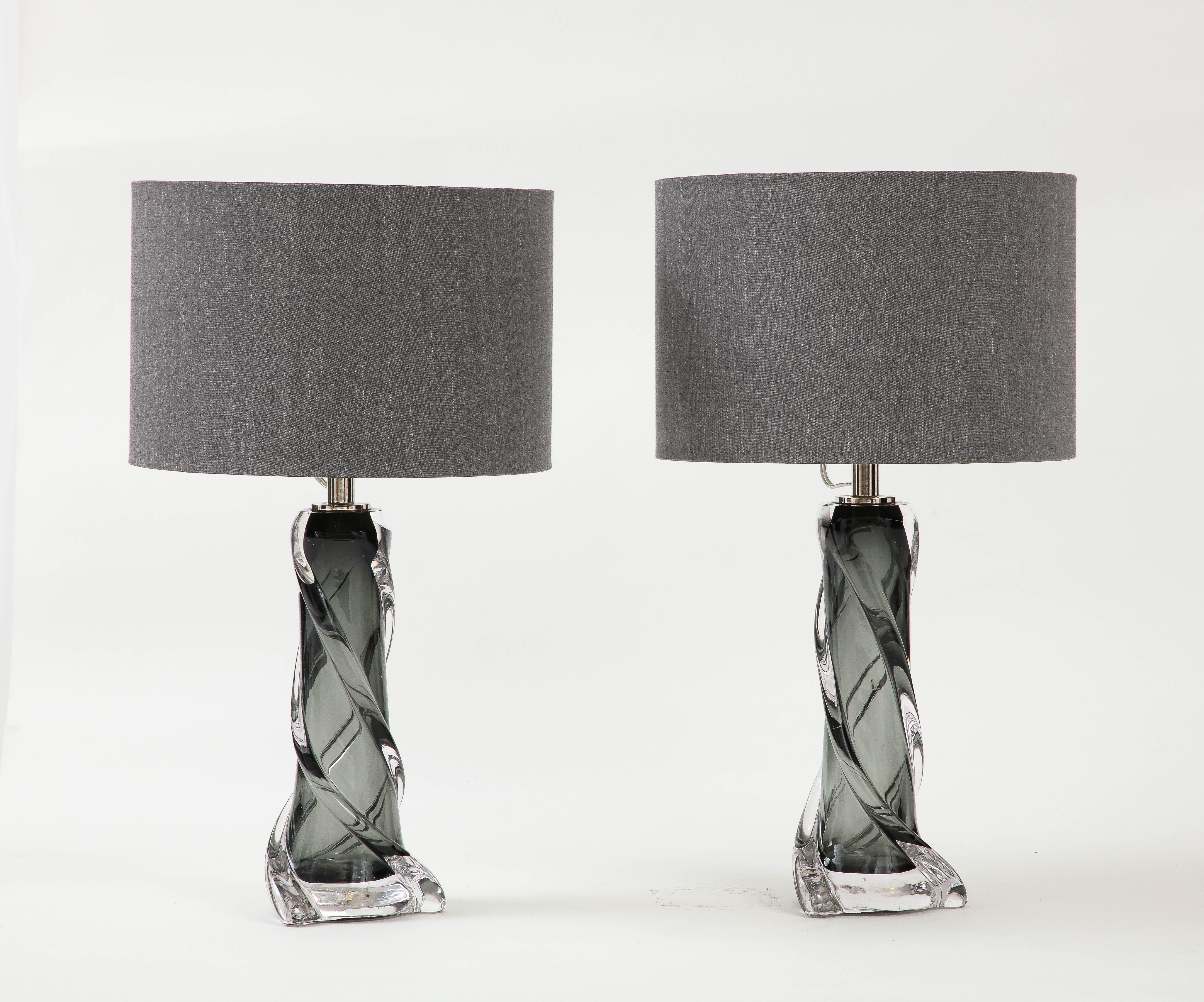 Pair of Hand blown clear and smokey quartz grey colored glass lamps, flanked by three twisting pieces of clear glass.
The lamps have been Newly rewired and come complete with grey silk shades. 
The dimensions of the shades are Height is 10