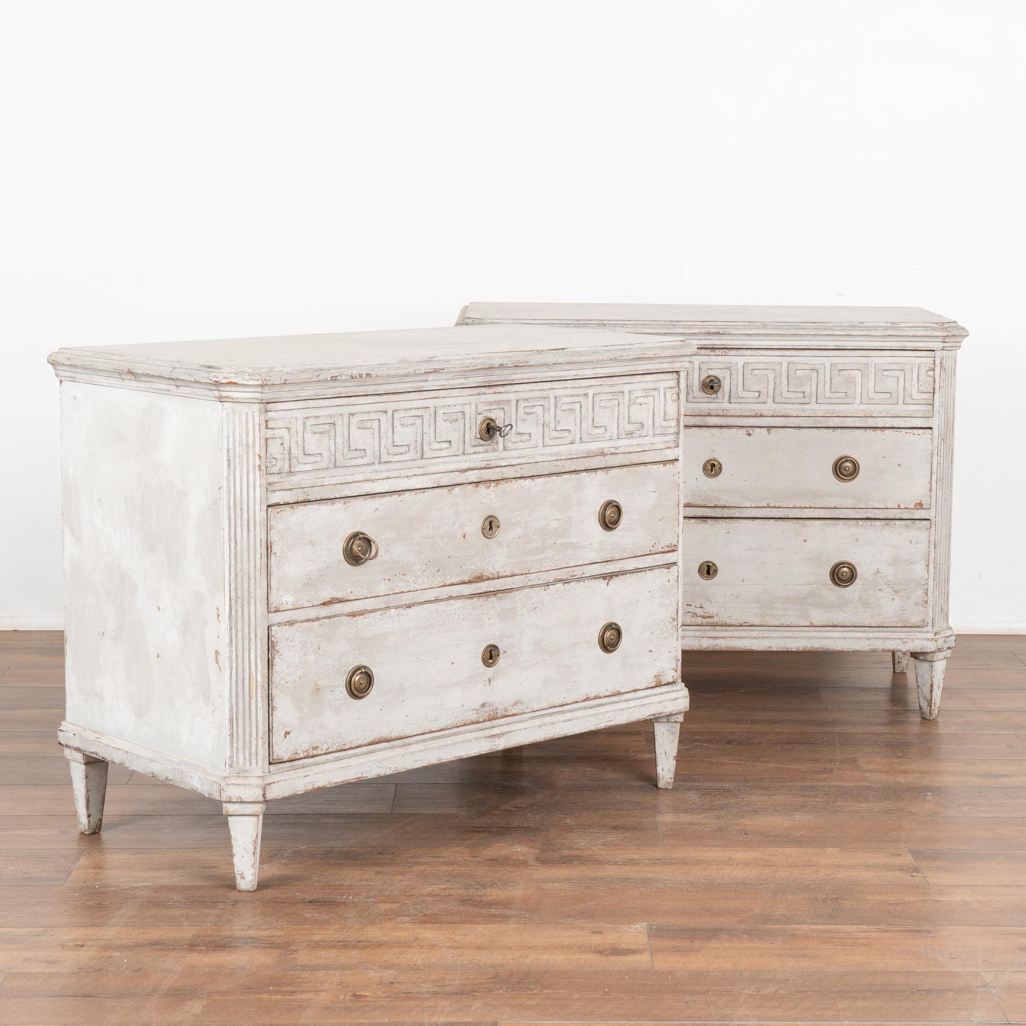 A pair of decorative Gustavian pine chest of drawers with Greek key motif carved in upper drawer.
Canted fluted side posts, 3 drawers resting on four tapered feet.
The newer, professionally applied gray custom painted finish is perfectly distressed