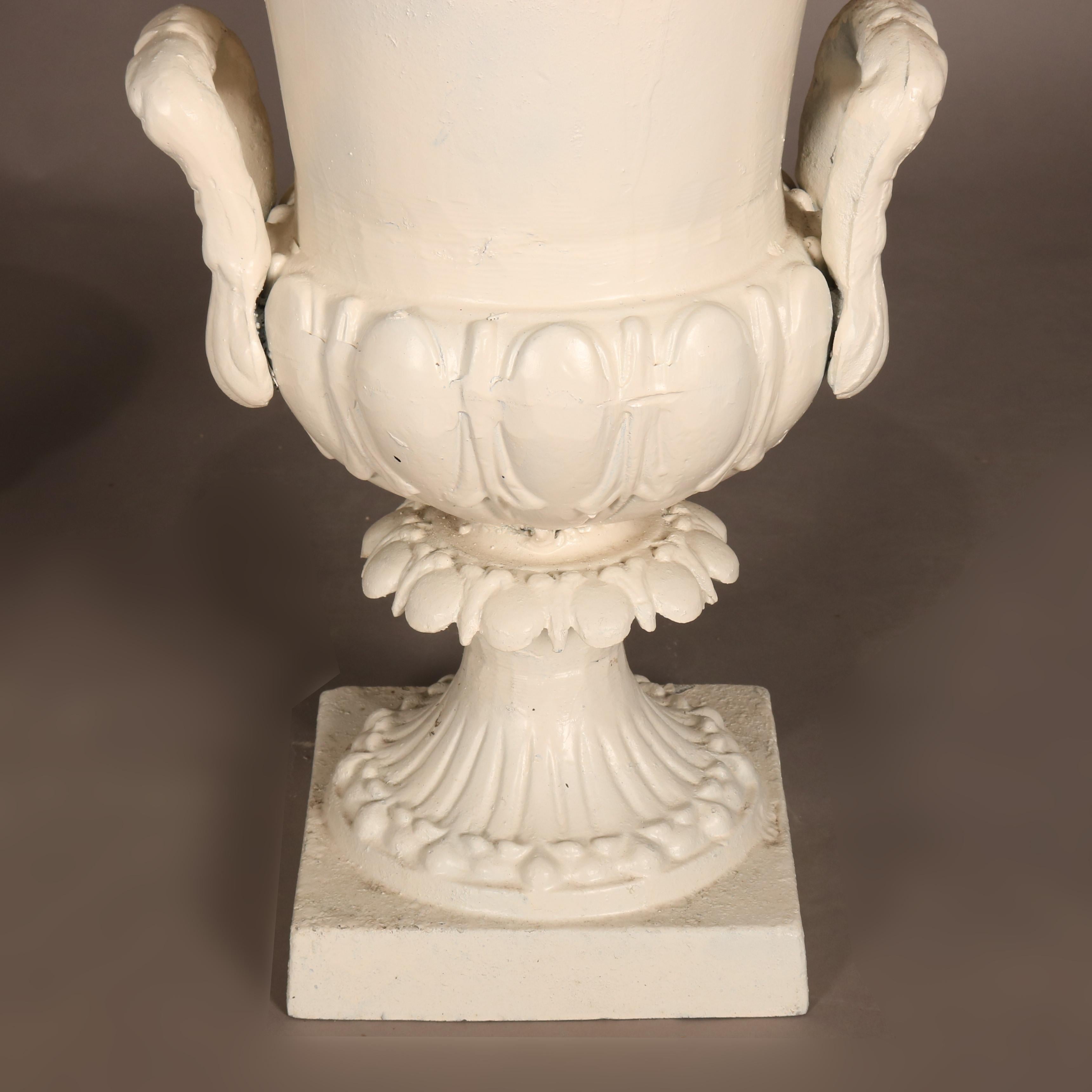 A pair of white painted tin Grecian style garden urns feature flared form bowl with reeded base and double handles surmounting decorated plinth seated on square feet, 20th century

***DELIVERY NOTICE – Due to COVID-19 we have employed