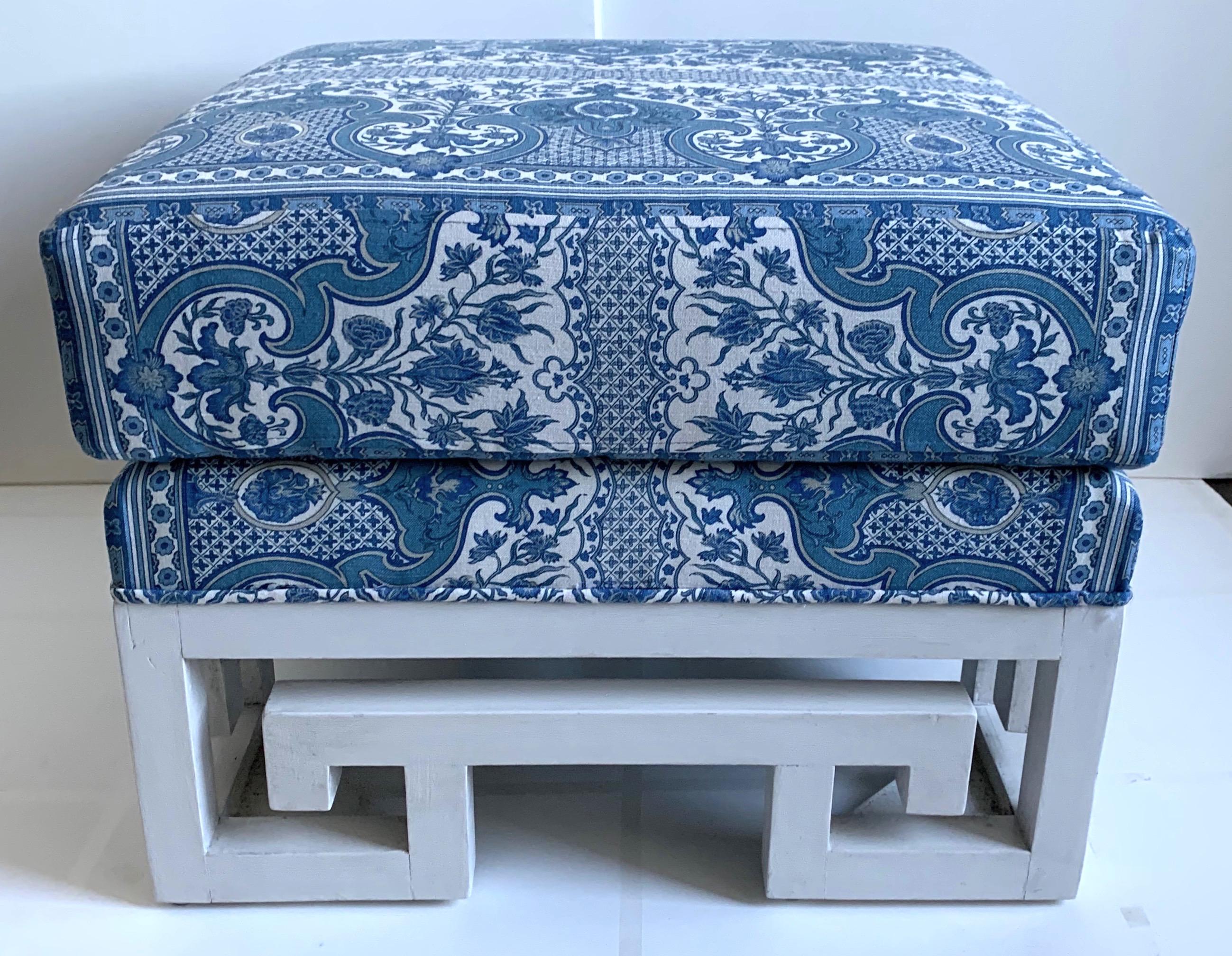 Pair of custom Greek key ottomans or stools. Newly repainted in an antique white finish. Custom designed with new fixed double stacked pillow cushions in Brunschwig & Fils Digby Tent printed blue linen. Base without cushion is 9” tall.