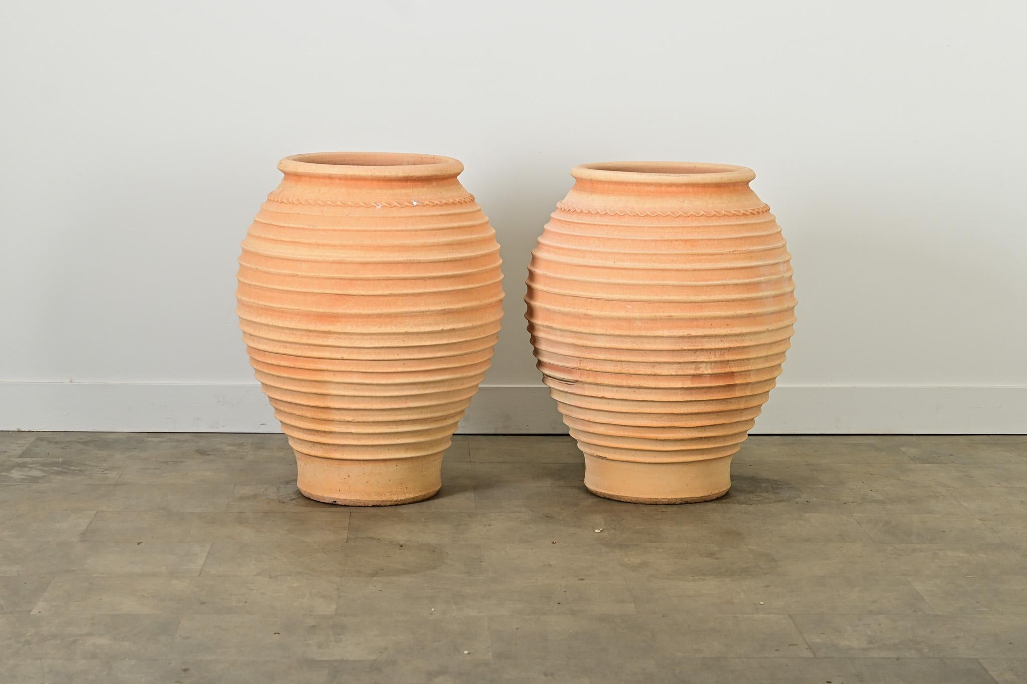 Una coppia di riproduzioni greche di vasi per piante provenienti da Creta, realizzati a mano in terracotta e simili a vasi per olive utilizzati fin dall'antichità nel Mediterraneo.  I vasi bulbosi sono ben decorati con dettagli a coste che