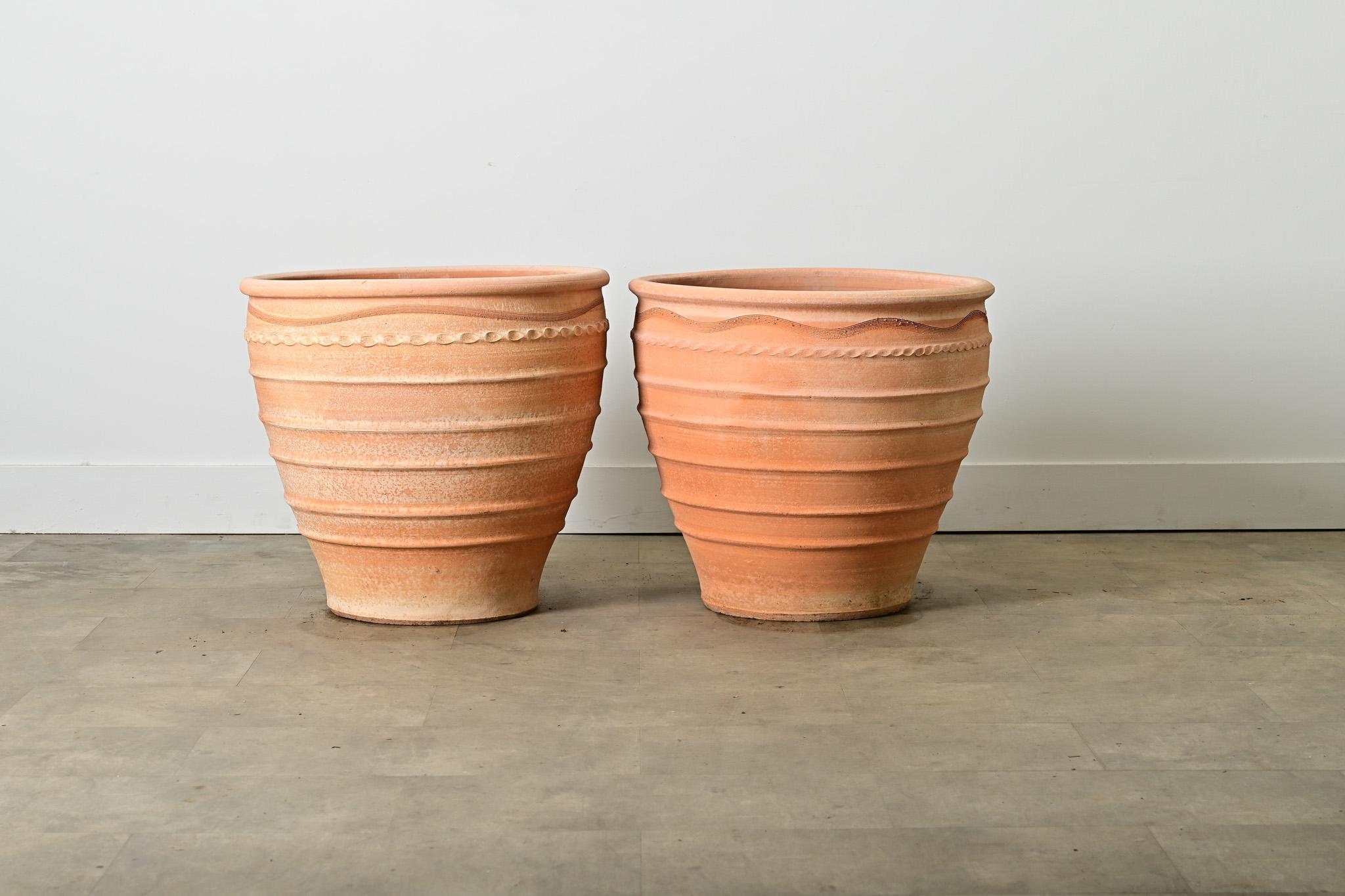 Una coppia di riproduzioni greche di vasi per piante provenienti da Creta, realizzati in terracotta e simili alle giare per olive utilizzate nella regione mediterranea fin dall'antichità. Questi vasi bulbosi sono ben decorati con una linea di onde