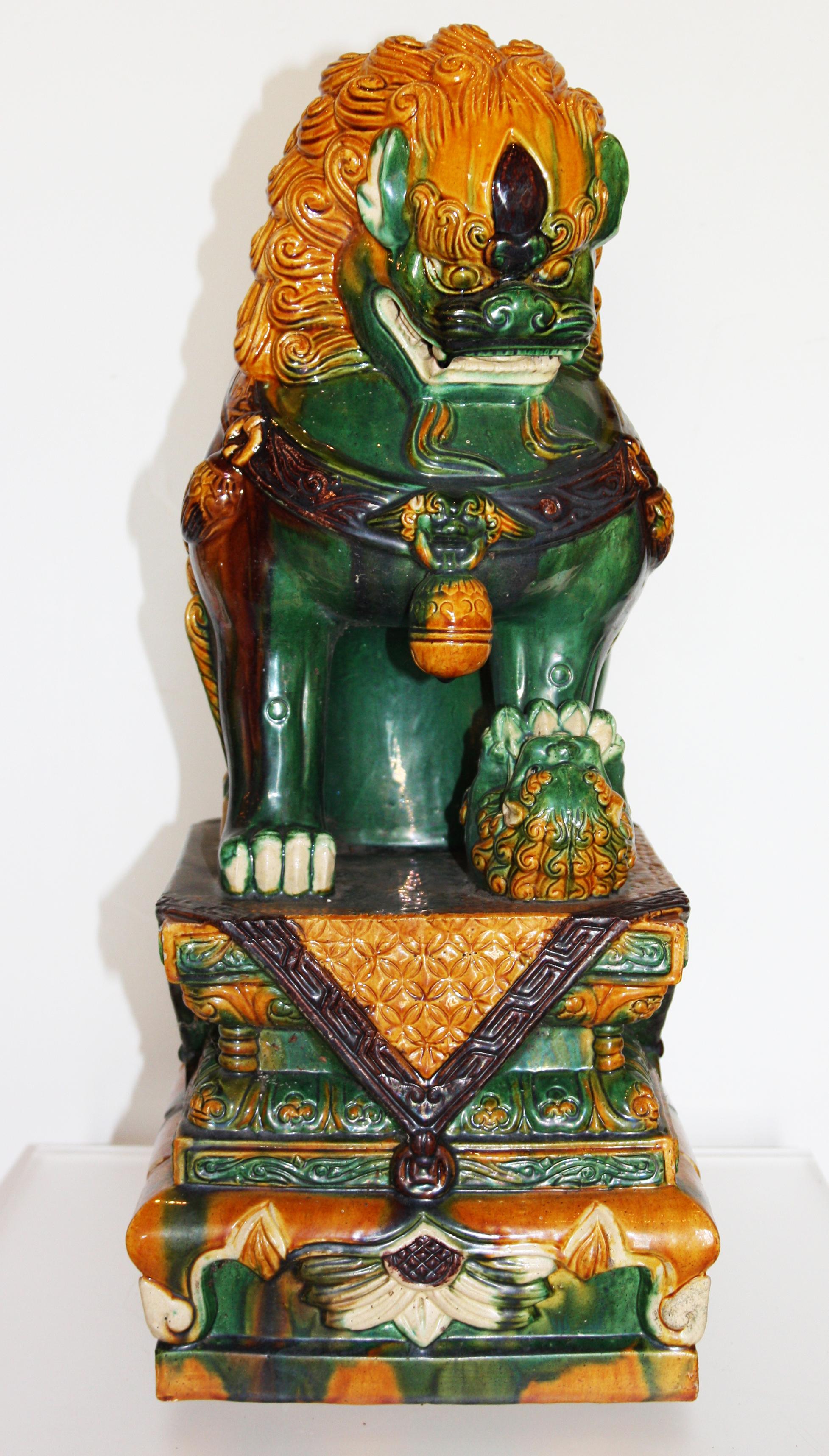 Pair of green and gold Chinese Sancai glazed foo dogs. The pair of dogs are sitting on platforms with their teeth bared. 


Dimensions given are for one dog.