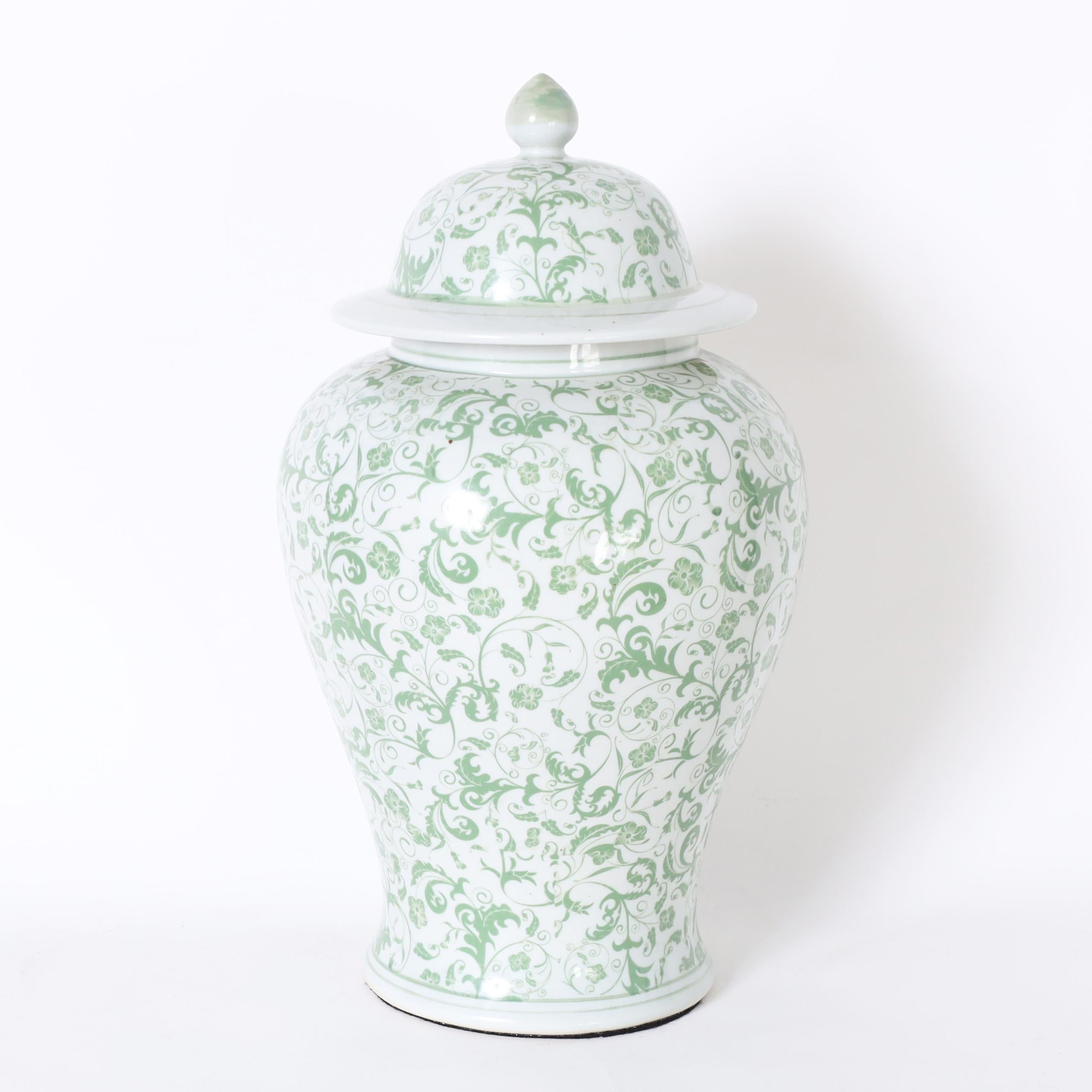 Unusual pair of Chinese green and white porcelain lidded urns or jars with classic form hand decorated with delicate flowers and leaves.