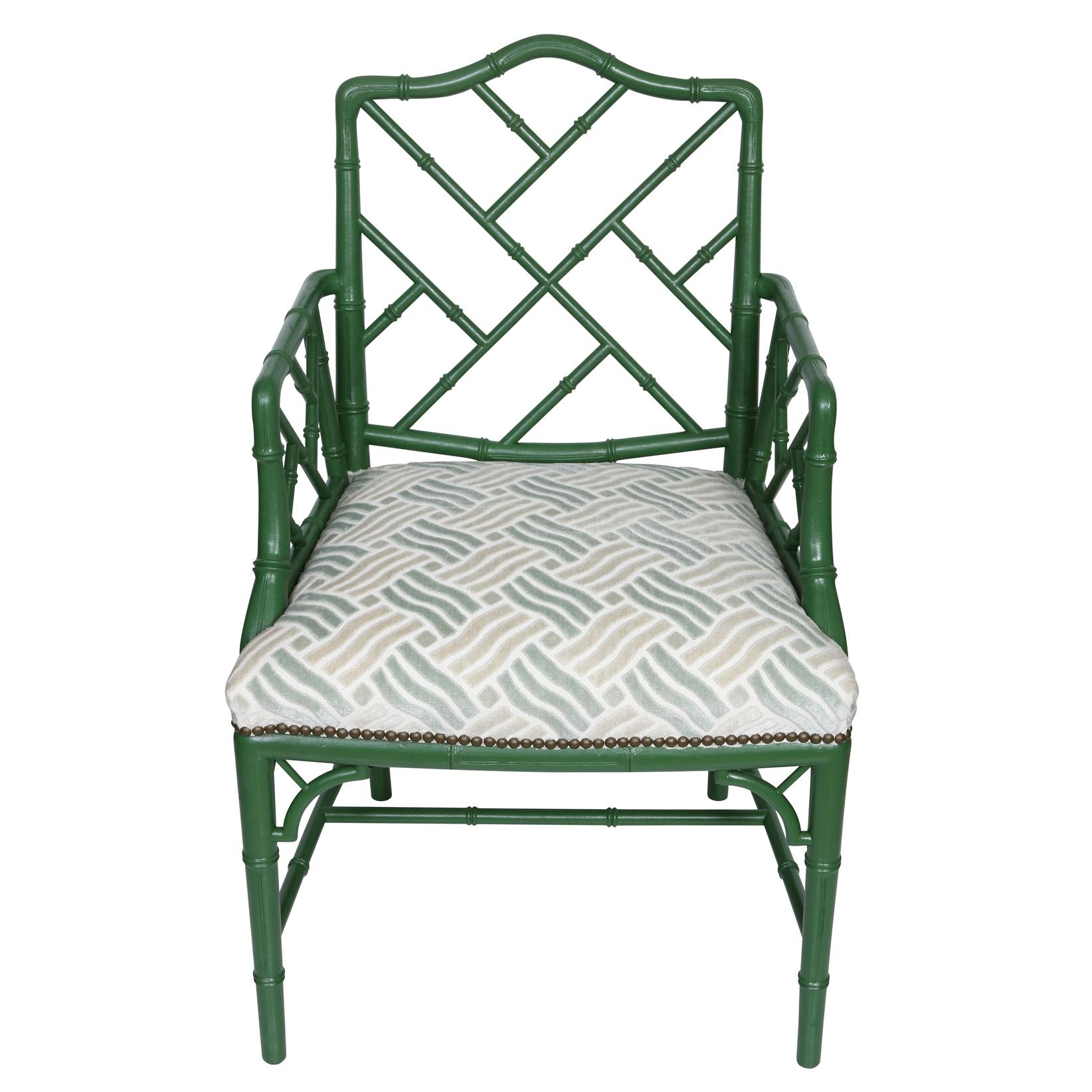 A pair of green wood, faux bamboo arm chairs with newly upholstered cut velvet seat cushions.  The newly painted green chair frames have a shaped back and diagonal bamboo design within the arms and back of each chair.  The legs are straight with a