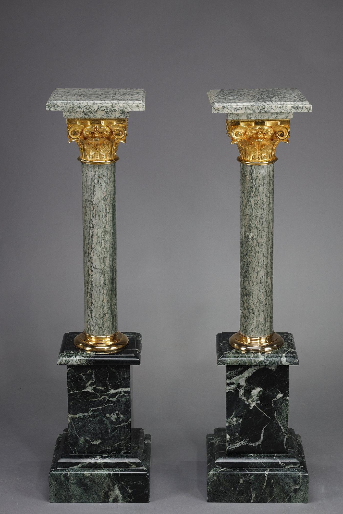 Ein Paar imposante Säulen aus grünem Estours-Marmor, gekrönt von einem korinthischen Kapitell aus vergoldeter Bronze und einer quadratischen Platte aus Estours-Marmor, ebenfalls 28 cm / 28 cm. Jede Säule ruht auf einem Sockel aus alpengrünem Marmor