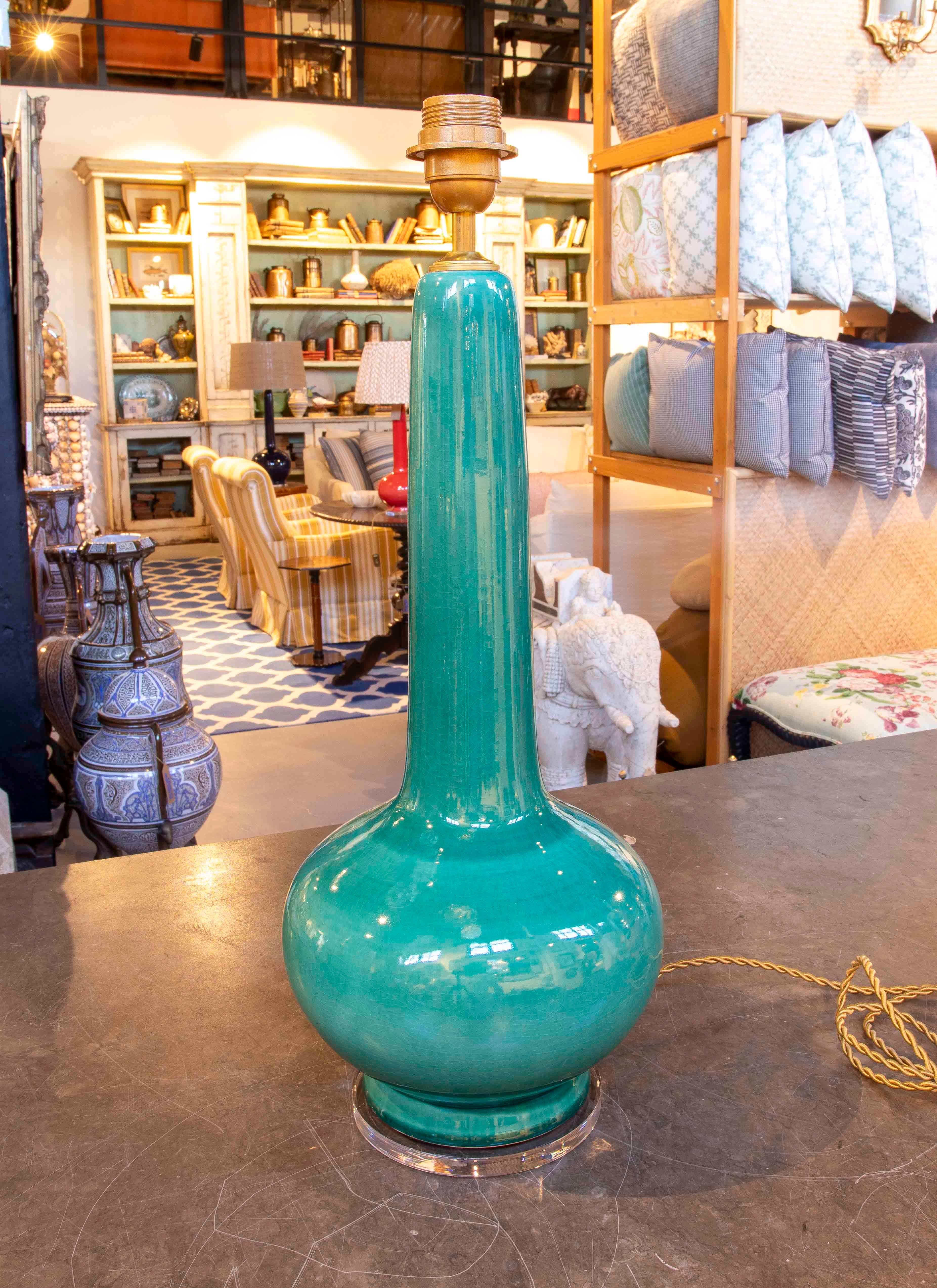An attractive pair of glazed ceramic table lamps in a vibrant jade green hue, with a glossy glaze finish that enhances their elegance. Their streamlined design, featuring a globular base and elongated neck, reflects the influence of oriental