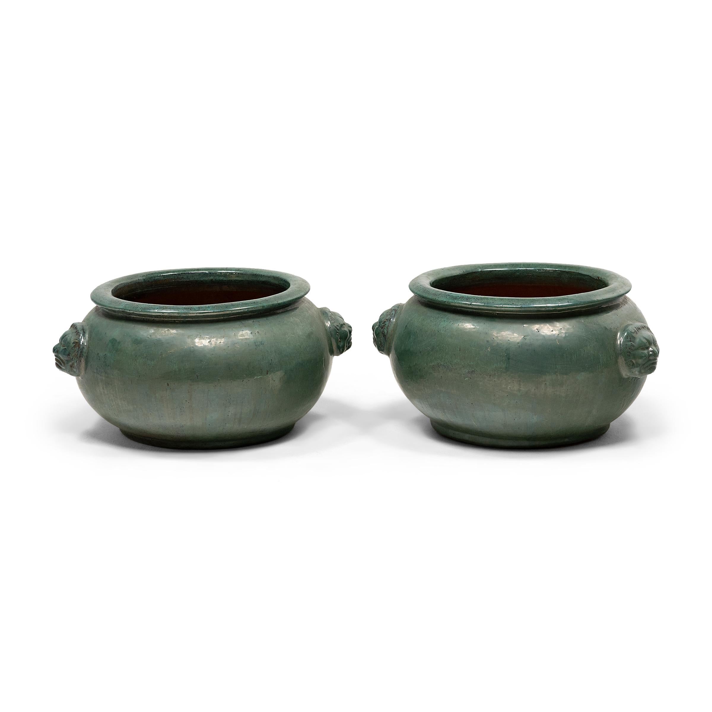This pair of monumental ceramic pots is glazed with a thick turquoise pigment that lingers beautifully on every imperfection. The basin has a round and tapered form, with a wide mouth, flared rim, and two side handles shaped in the face of an