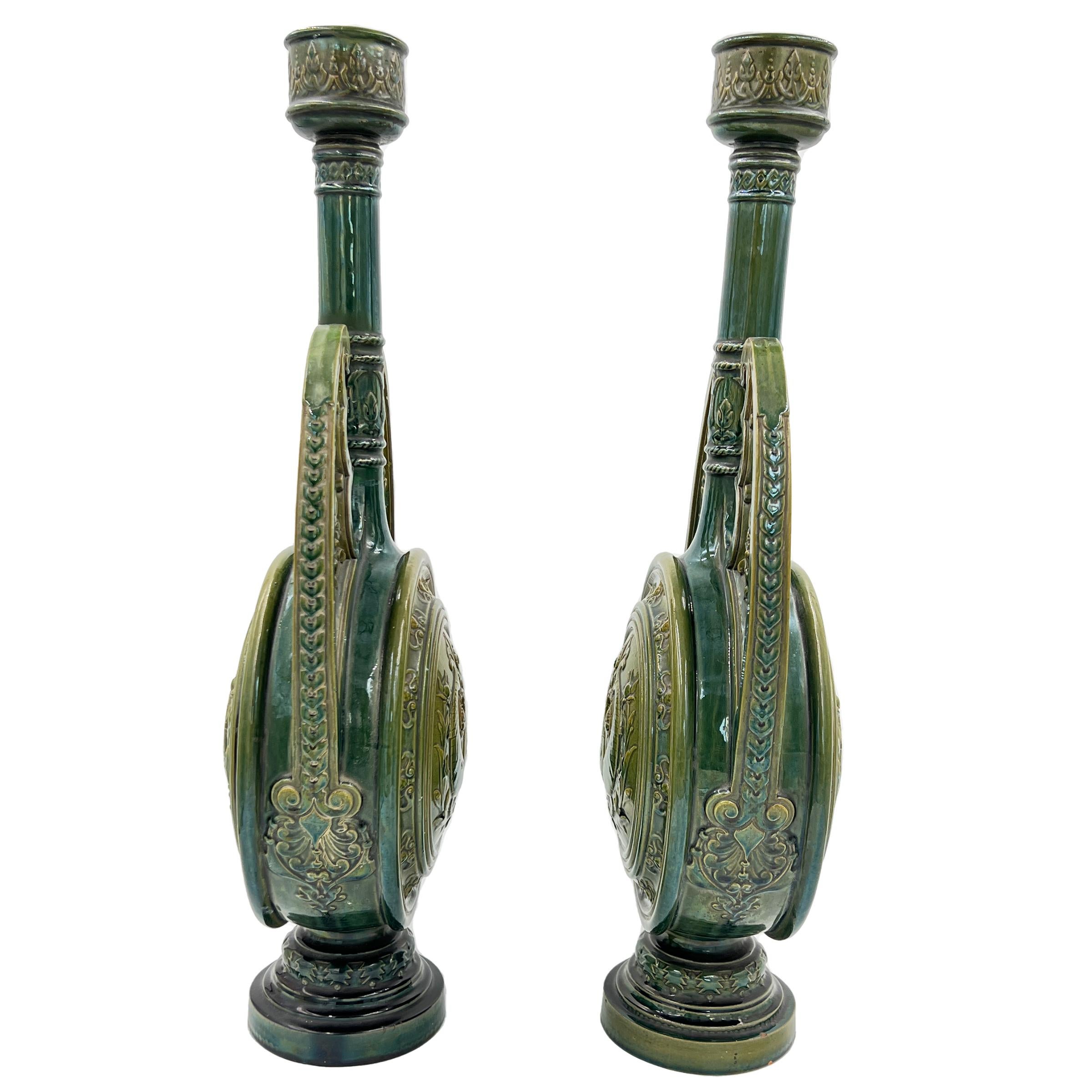 A fine 19th century pair of green glazed candlesticks with fish motifs on the circular body.