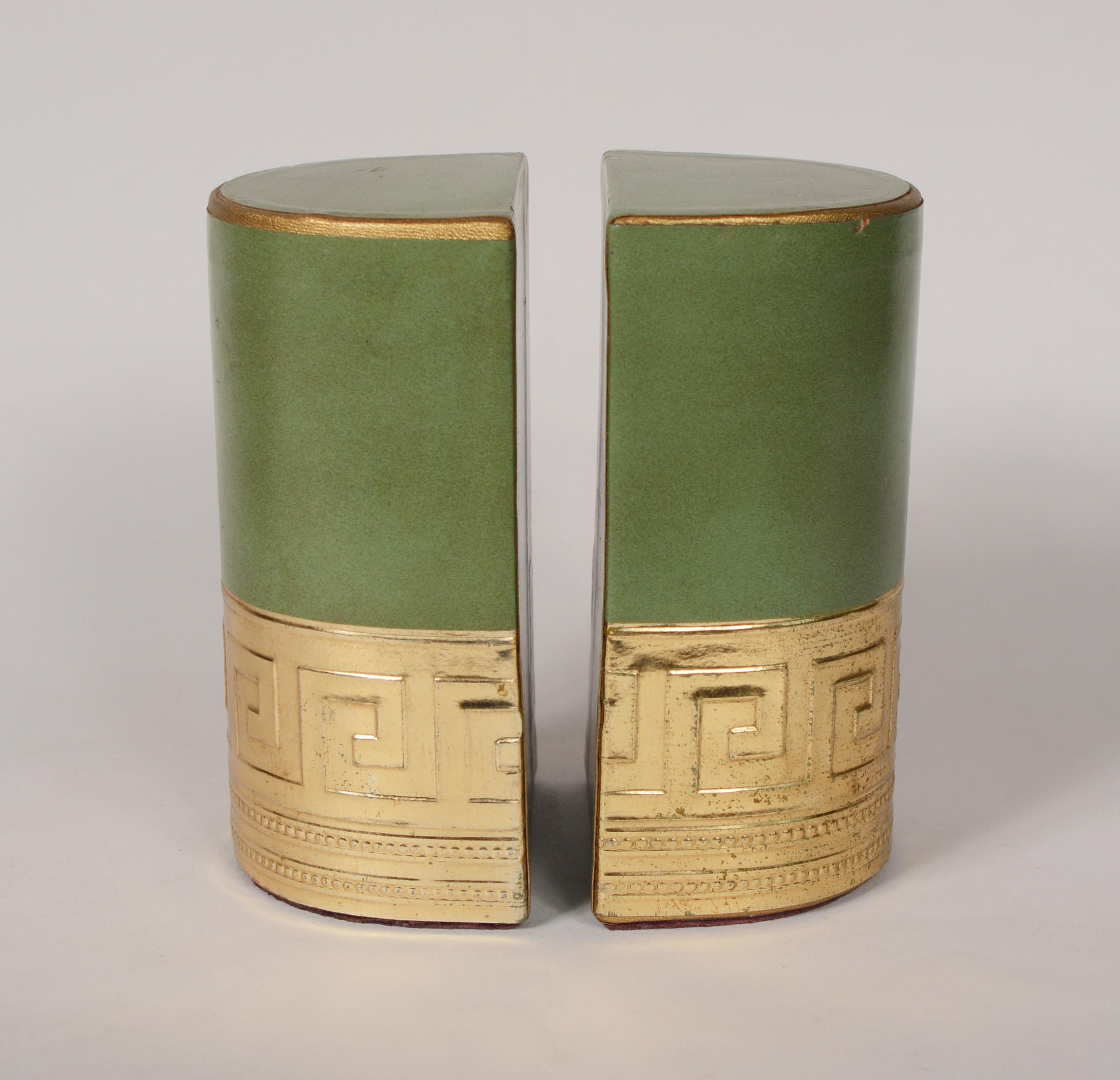 Pair of leather covered bookends with a Greek key design in a brass colored foil paper. These are likely Italian. There is a loss in the foil paper at the center front of both and a small ding on the top edge of one. There is discoloration to the