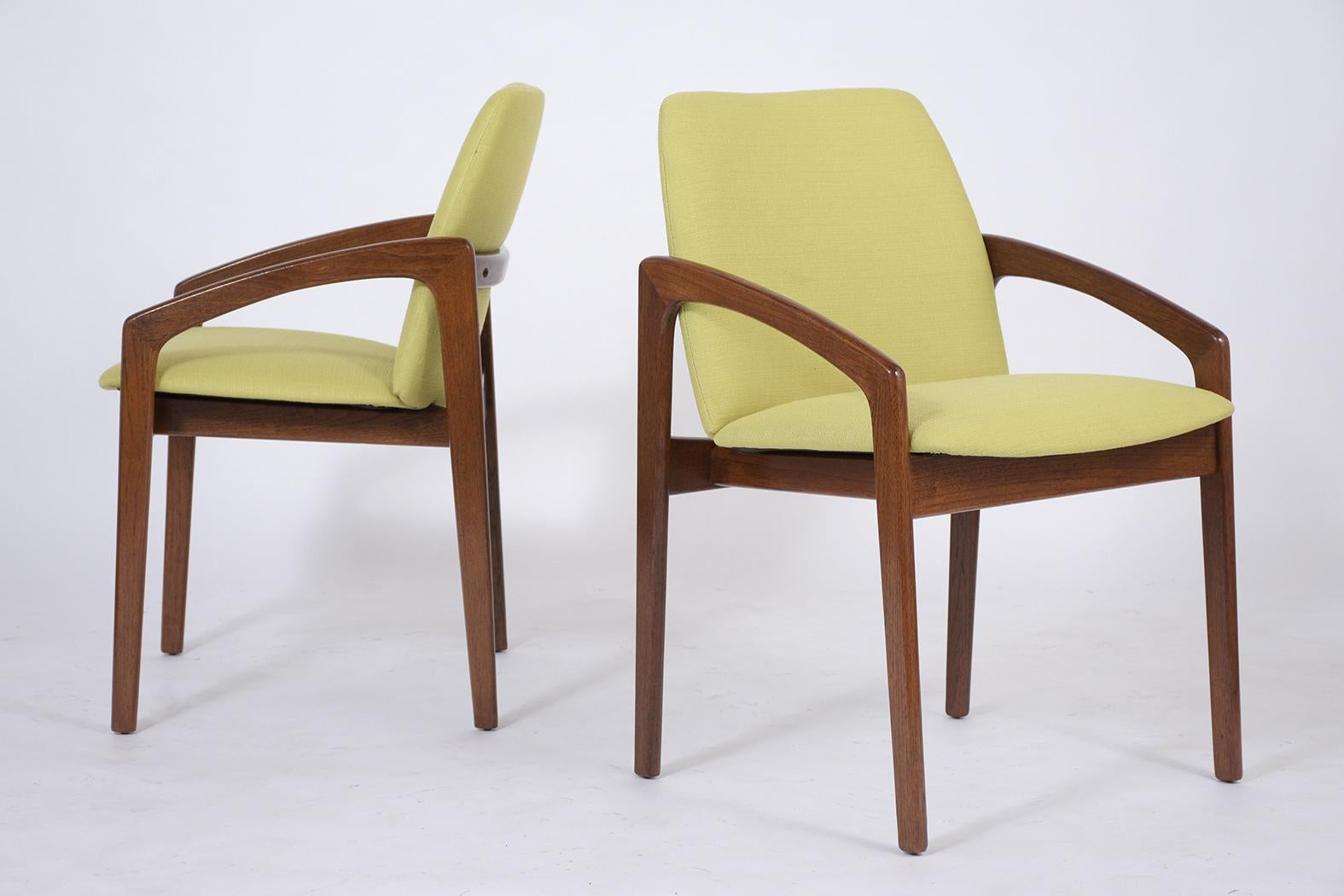 This pair of vintage 1960 mid century modern armchairs are crafted out of teak wood with a newly stained rich mahogany color lacquered finish and have been completely restored by our team of expert craftsmen in house. The set of side chairs have