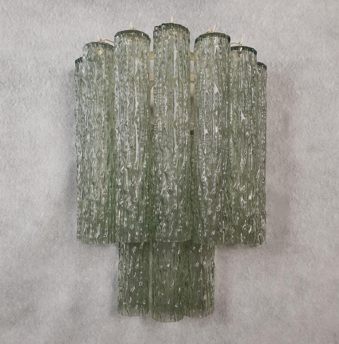 Pair of large Murano glass sconces, Mid century modern. Attributed to Mazzega, Italy 1970s.
The sconces are made of olive green Murano glass tubes, on two tiers.
The tubes are veined, textured outside.
The frame is painted ivory.
Each sconce has 3