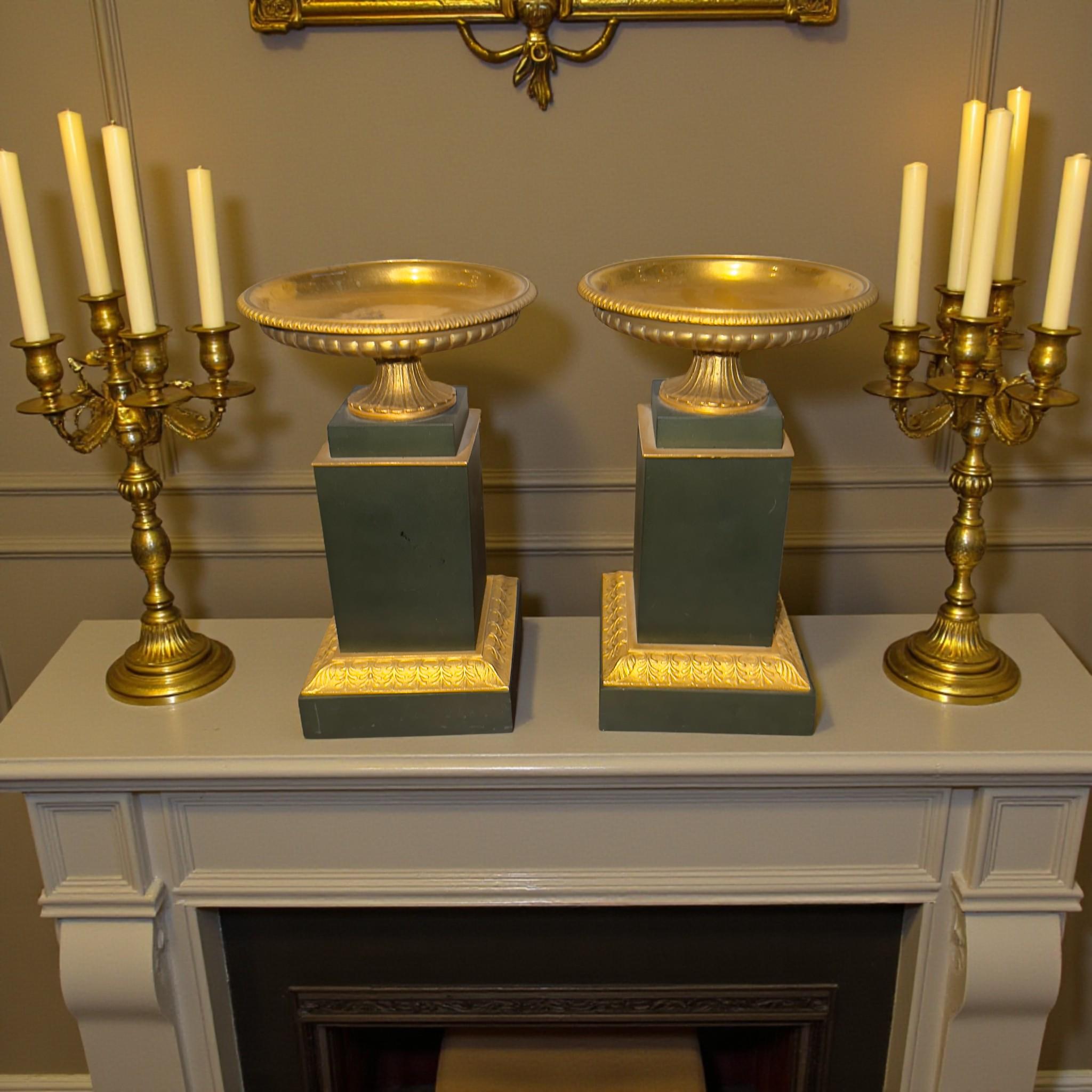 Una coppia di eleganti tazze in bronzo in stile Eleg. Queste ciotole decorative sono realizzate in bronzo dorato e poggiano su alti piedistalli con una patina scura e opaca. Il contrasto tra la superficie scura e profonda e l'oro caldo evidenzia le