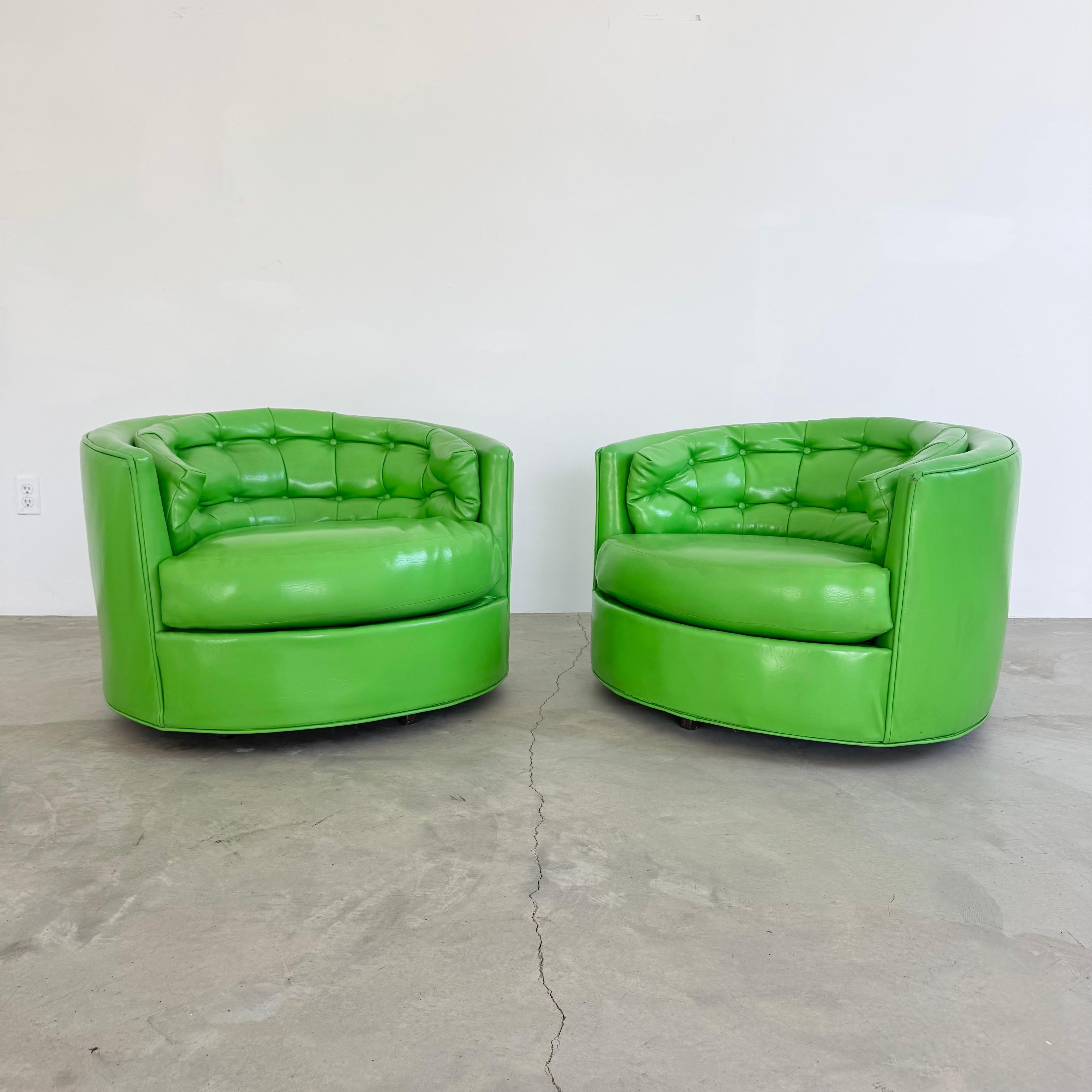 Ajoutez une déclaration audacieuse à votre intérieur avec cette paire frappante de chaises longues pivotantes vintage à dossier en tonneau en vinyle vert vibrant. Avec leurs formes arrondies, leurs dossiers profondément touffus et leurs généreux