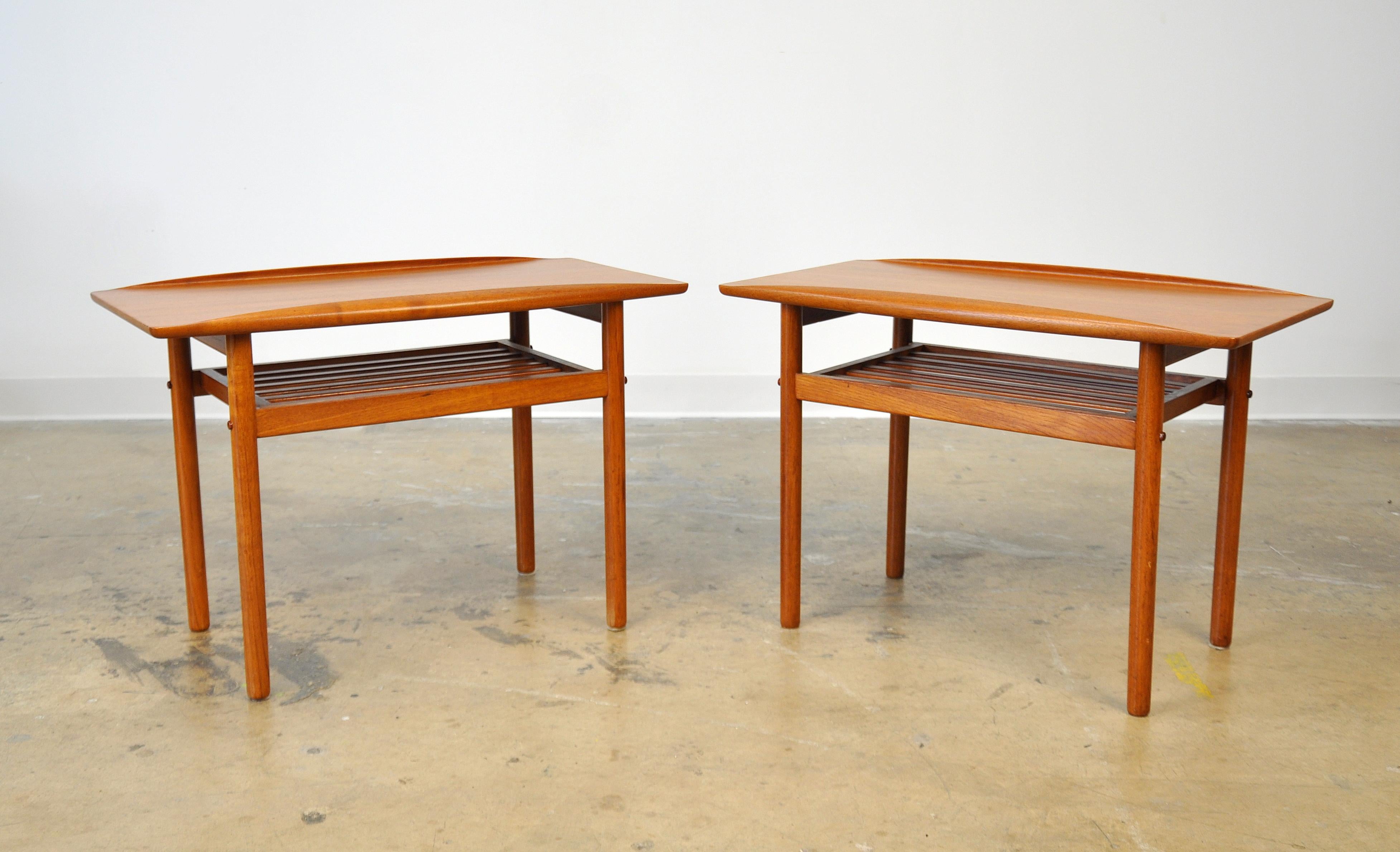 A pair of midcentury Danish modern two-tier end tables designed by Grete Jalk, manufactured by Poul Jeppesen, dating from the early 1960s. Each occasional table features sculpted raised edges, a distinctive feature of Jalk's designs, and a slatted