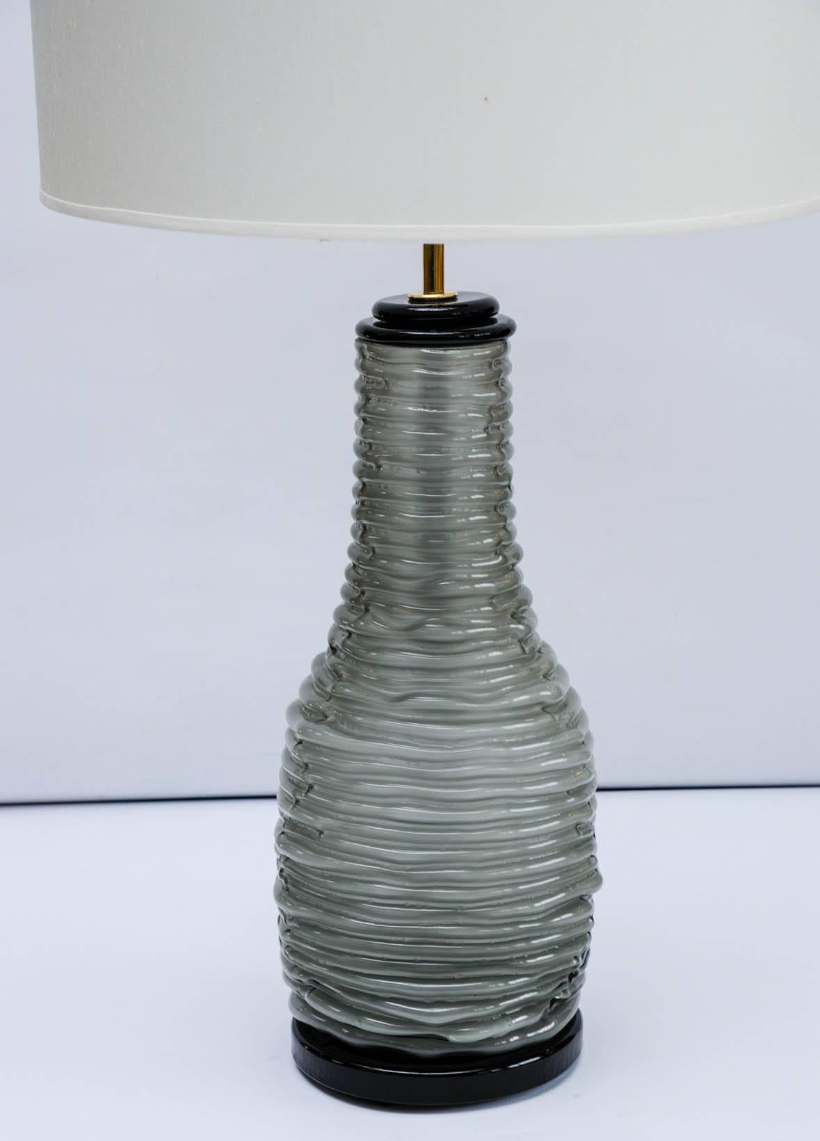 Paire de belles lampes de table raffinées en verre de Murano gris et noir et monture en laiton.

Le corps gris a une texture spéciale qui donne l'illusion optique d'une corde empilée sur elle-même pour former la lampe.