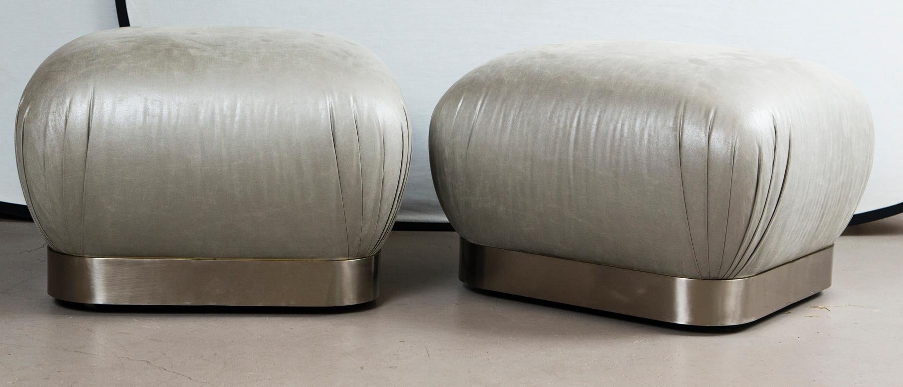 Pair of grey leather and stainless steel Karl Springer Souffle ottomans on wheels.