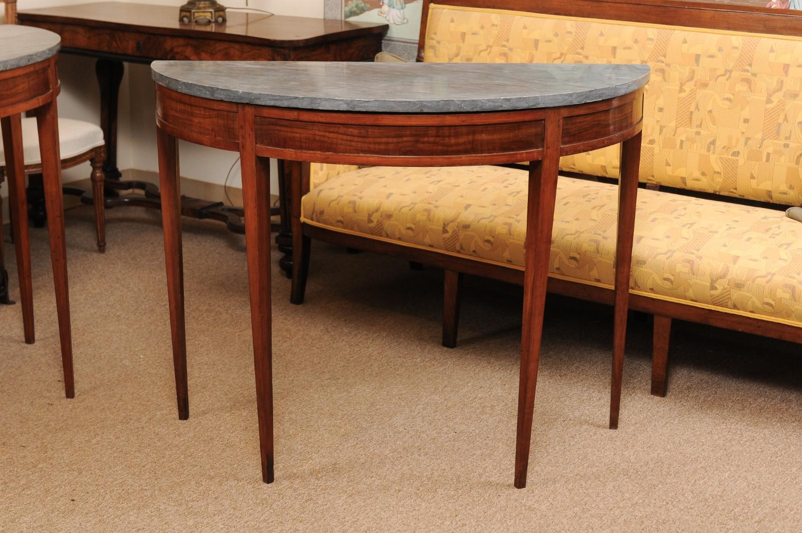 A pair of late 19th century fruitwood demilune console tables featuring grey marble tops and tapered legs.