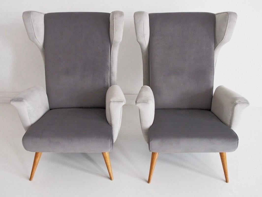 Paire d'élégants fauteuils datant des années 1950. Structure et pieds en bois teinté, nouvellement tapissés dans deux tons de tissus de velours gris. Sièges très confortables.
