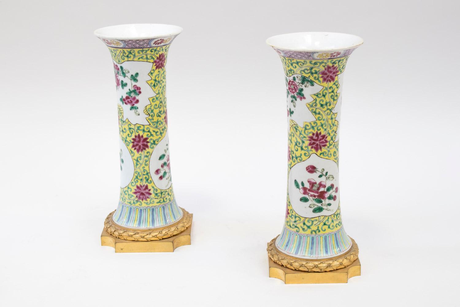 Small gu-form porcelain vases decorated with pink family enamels on a yellow background with green interlaces. Decoration of white background cartouches with pink dahlias.
Geometric friezes on the base and the collar of the vases.
Louis XVI style