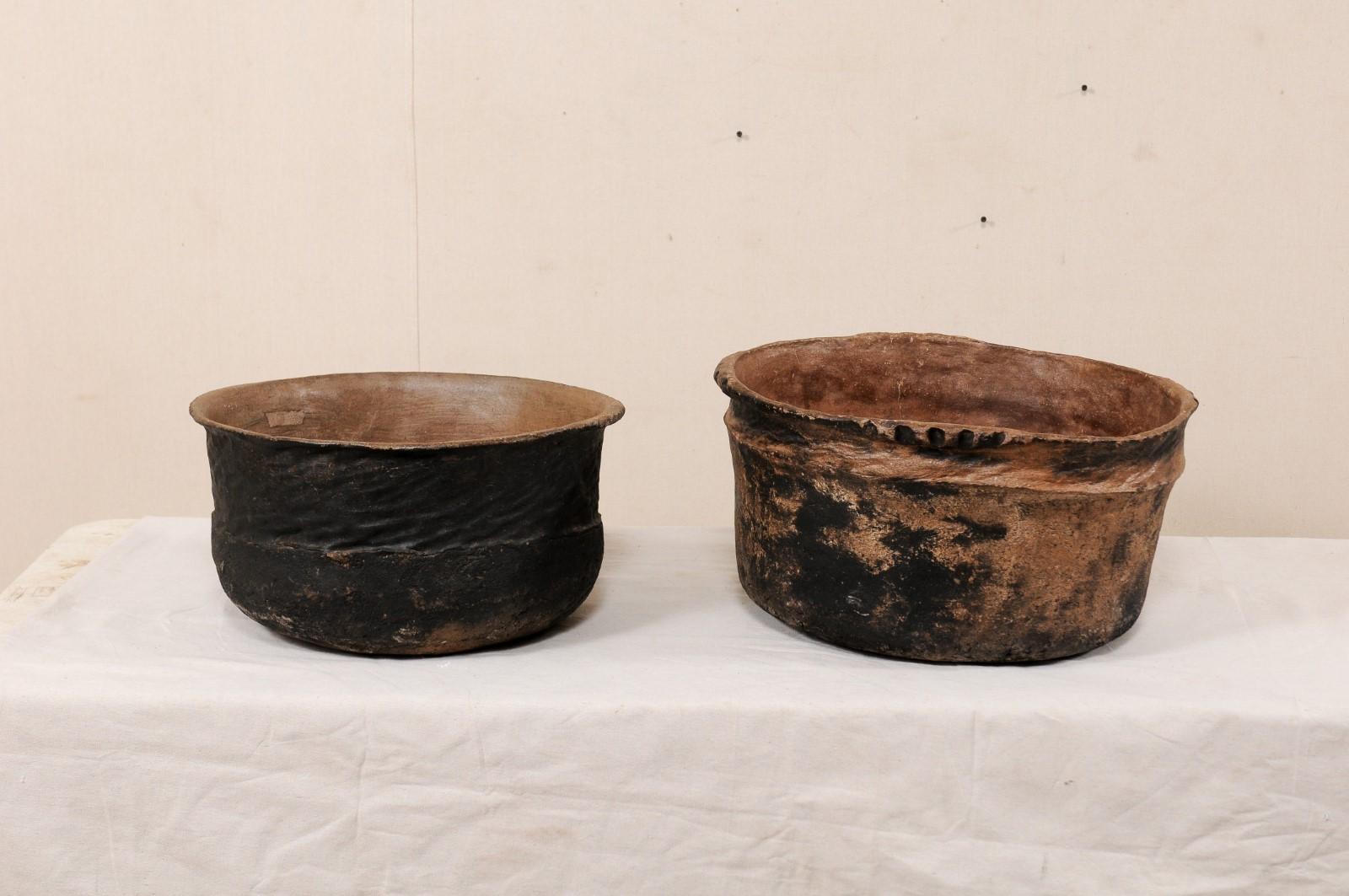 A pair of Guatemalan clay cooking pots from the early 20th century. These antique vessels from Guatemala made of clay, each have rounded forms with rustic, decorative texture on their exteriors. They have a darker exterior and a wonderful old patina