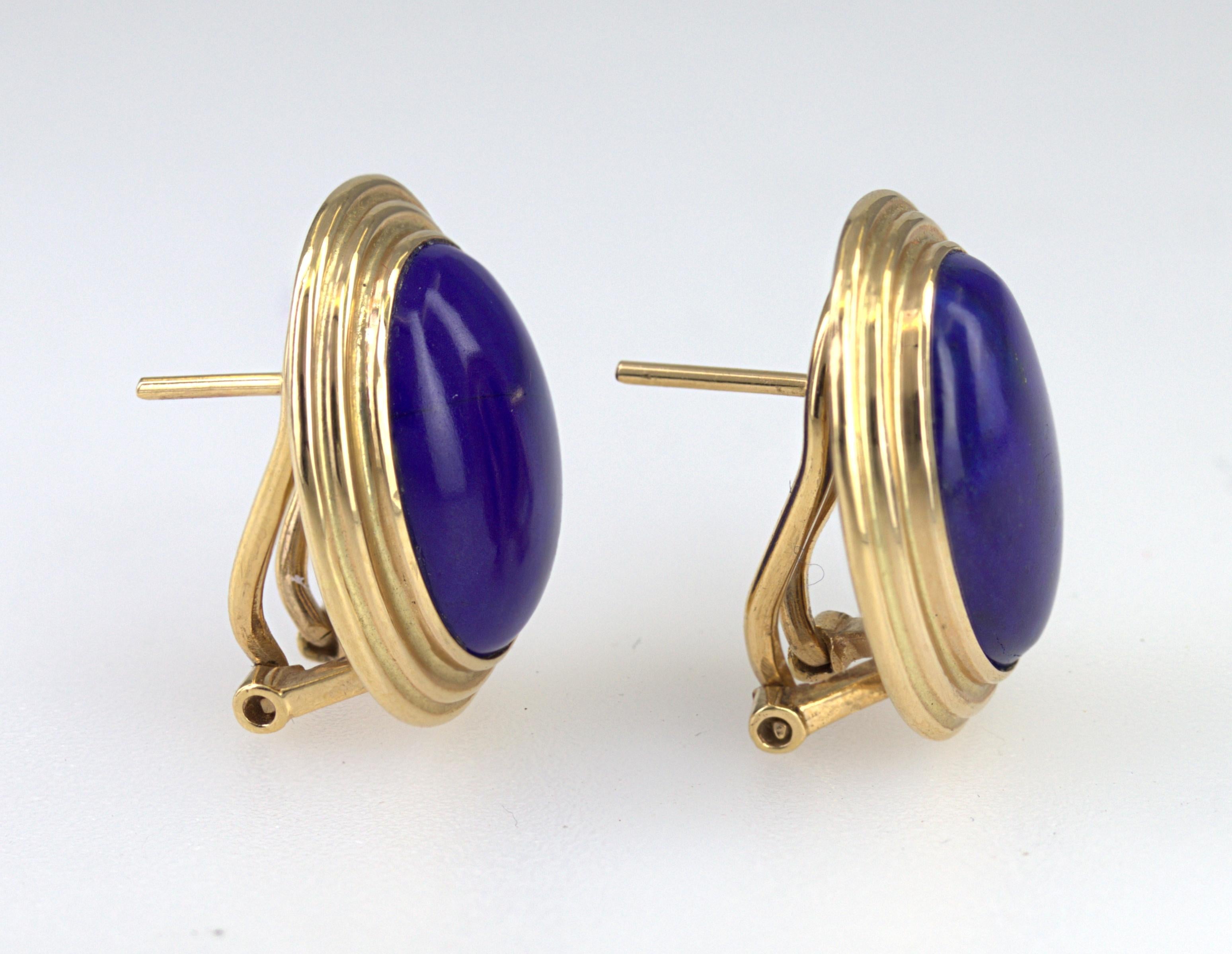 Featuring (2) oval lapis lazuli cabochons, 14 X 9 mm, bezel set and framed in 14k yellow gold mountings, 18 X 14 mm, completed with post and omega back, Gross weight 6.60 grams.