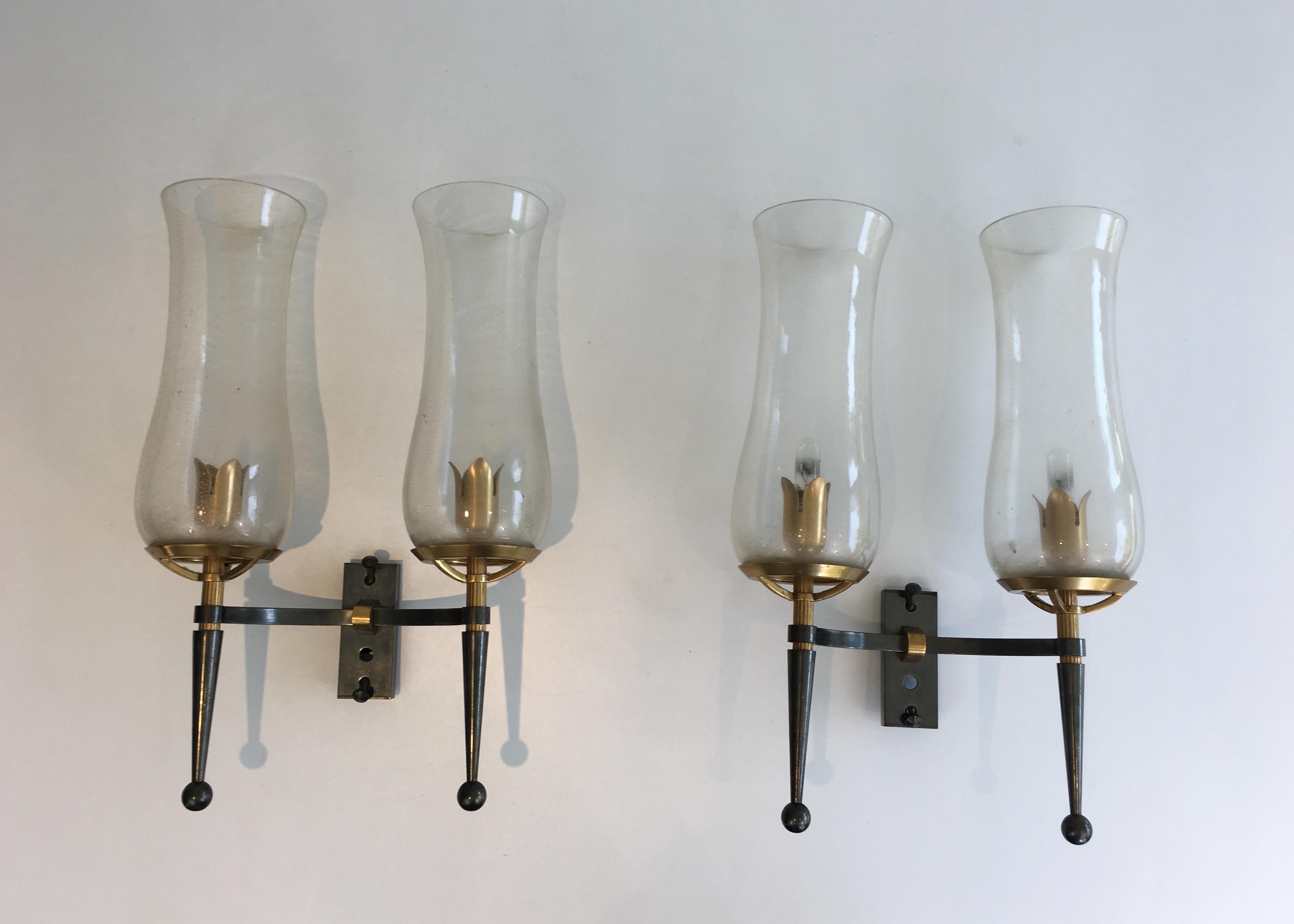 This beautiful pair of wall lights is made of gun metal steel and gilt bronze and brass. These wall sconces have very nice champagne Murano glass reflectors. They are probably a combination of a French designer and an Italian glass maker. Very nice