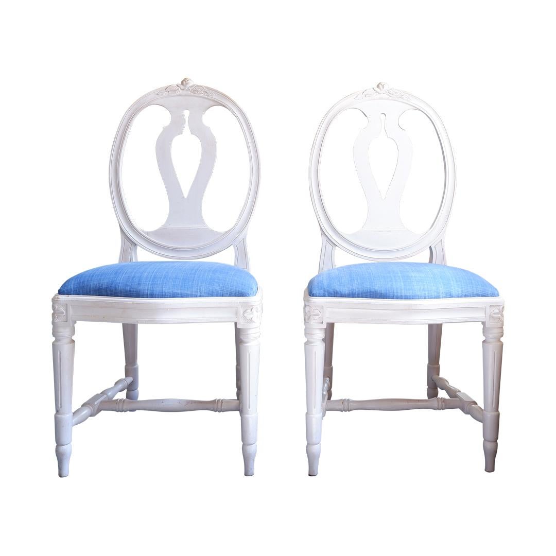 A set of 2 gustavian rose carved chair with hand carved single rose detailing to the top of the chairs. Antique off-white aged paint finish. Solid beech wood with an upholstered drop in seat. New fabric on upholstered seats. Each chairs is: width: