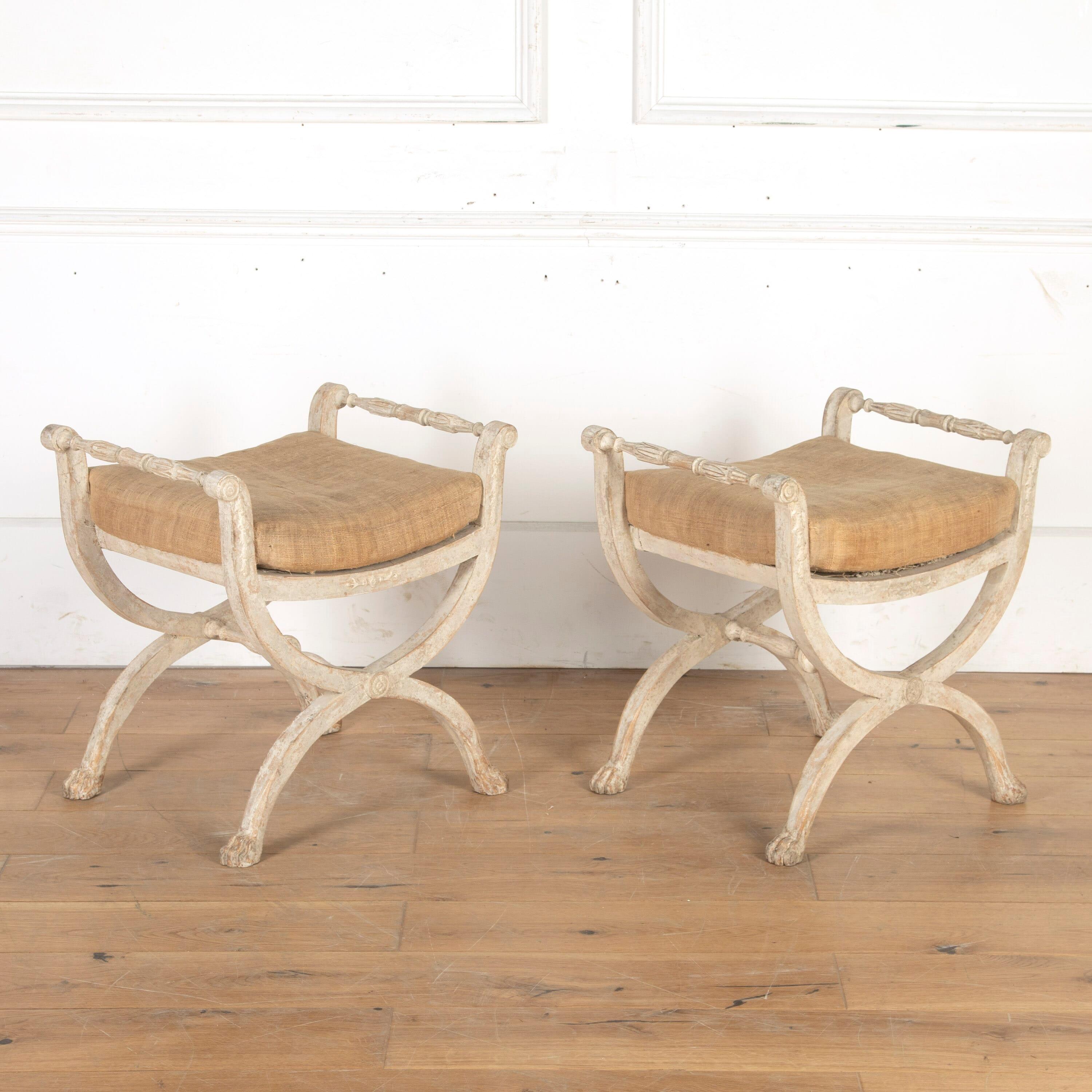 Pair of early 19th century Swedish Stockholm-made stools.

The seats are supported within an elegant yet substantial cross-form frame that terminates in carved lion's paw feet. 

Featuring decorative carving to the gently outscrolled armrests.
