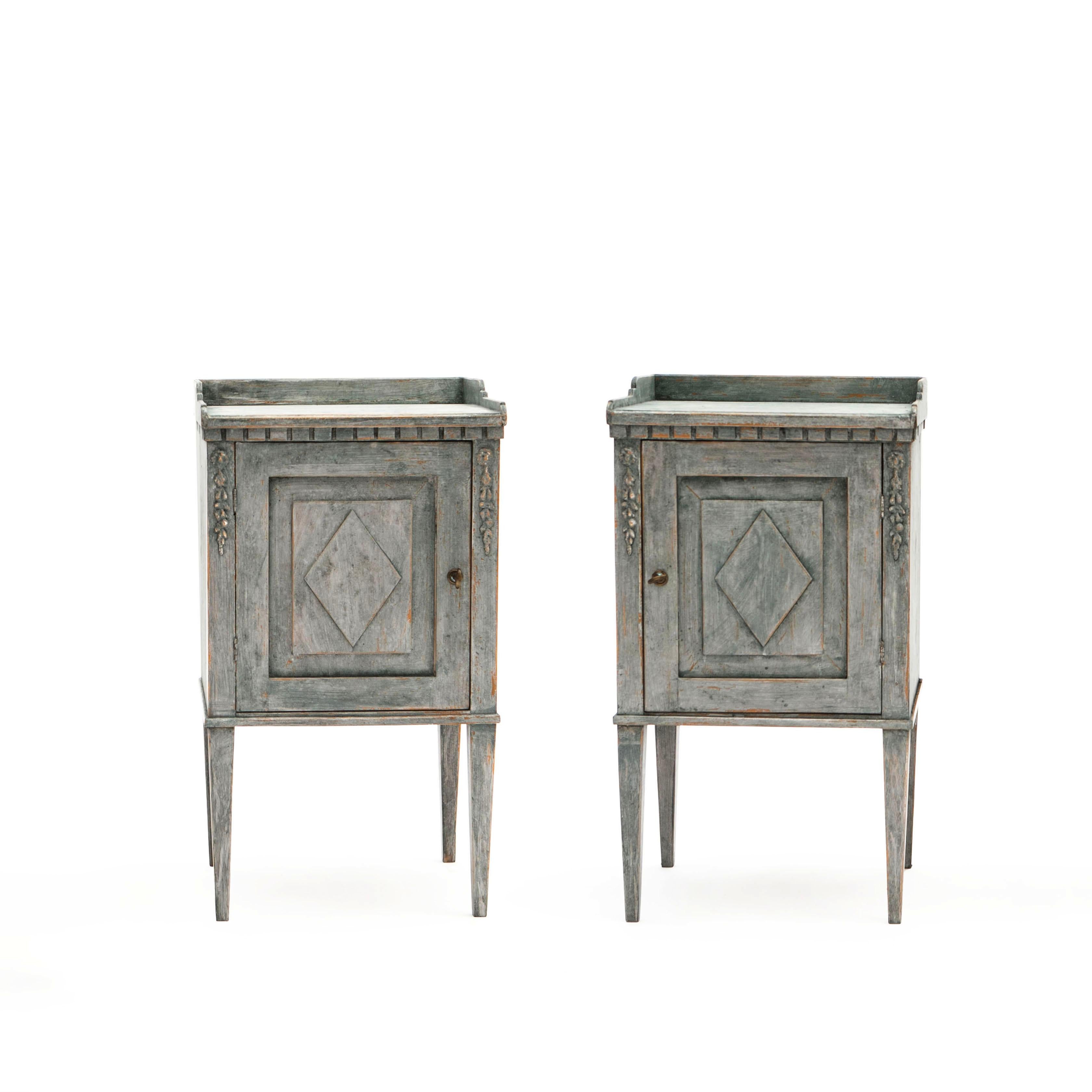 A pair of Swedish Gustavian style painted wood side cabinets / bedside cabinets from the mid 19th century.
These soft blue green painted cabinets feature a rectangular top with three-quarter gallery, sitting above a carved dentil molding. The façade