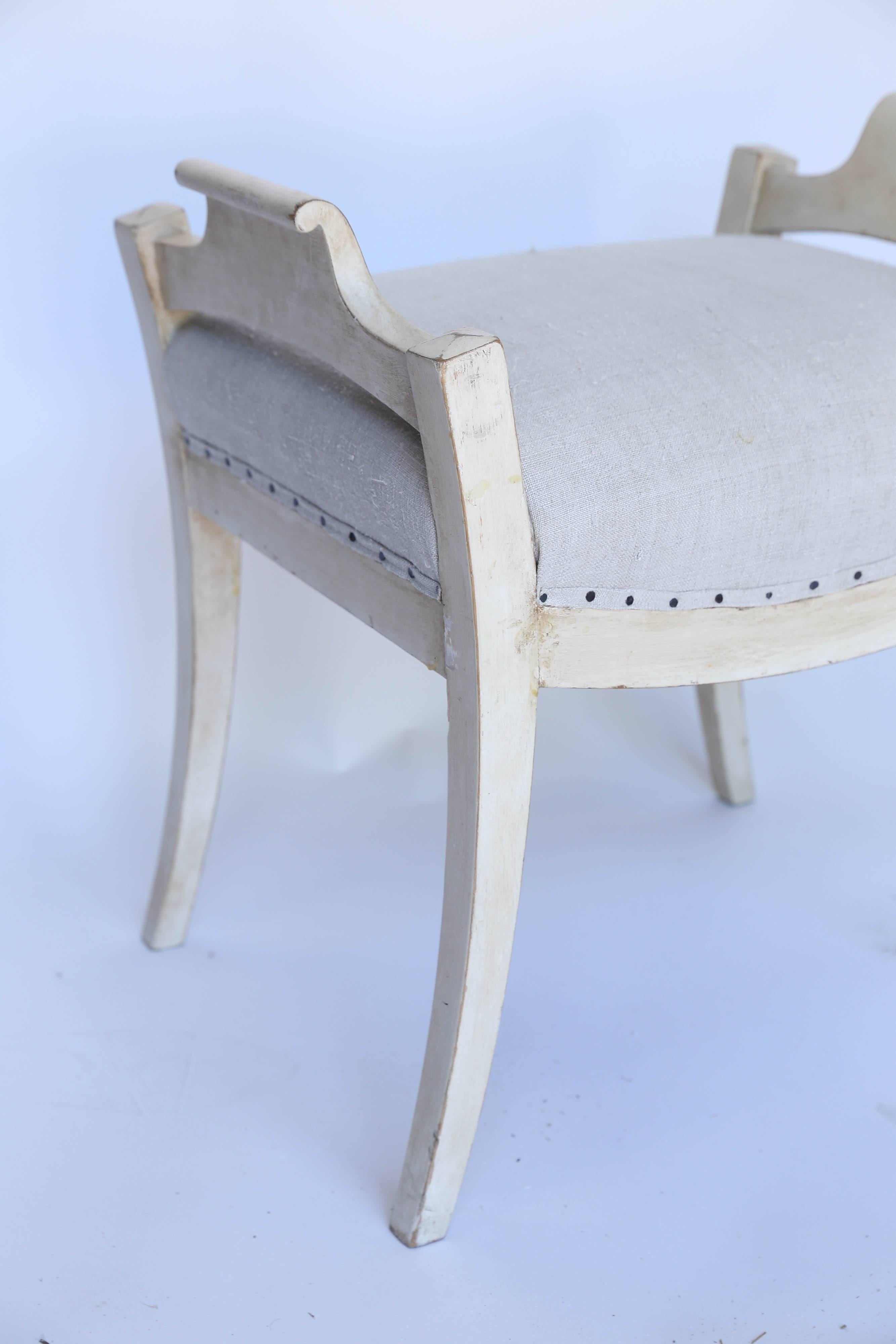 A charming pair of Gustavian style benches found in France. Newly upholstered in off-white linen with exposed upholstery tacks, these beautifully proportioned benches have gently worn off-white paint. Solid, sturdy and eye-catching.