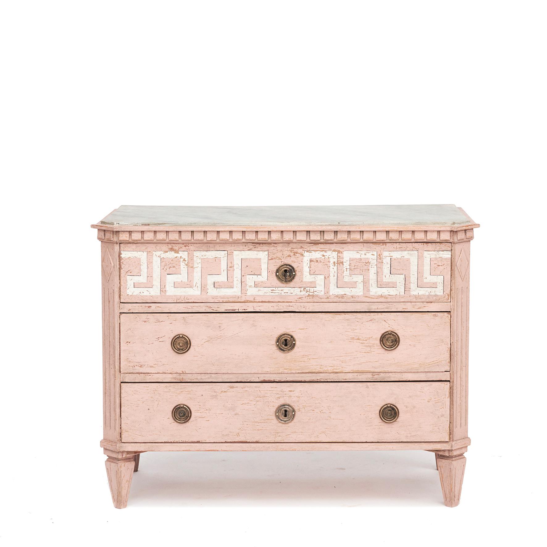 A pair of decorative Swedish Gustavian Style chest of drawers painted in dusty rose.
Wooden blue-gray faux marbled tabletop and dentil moldings.
Three drawer, upper drawer decorated with white painted 