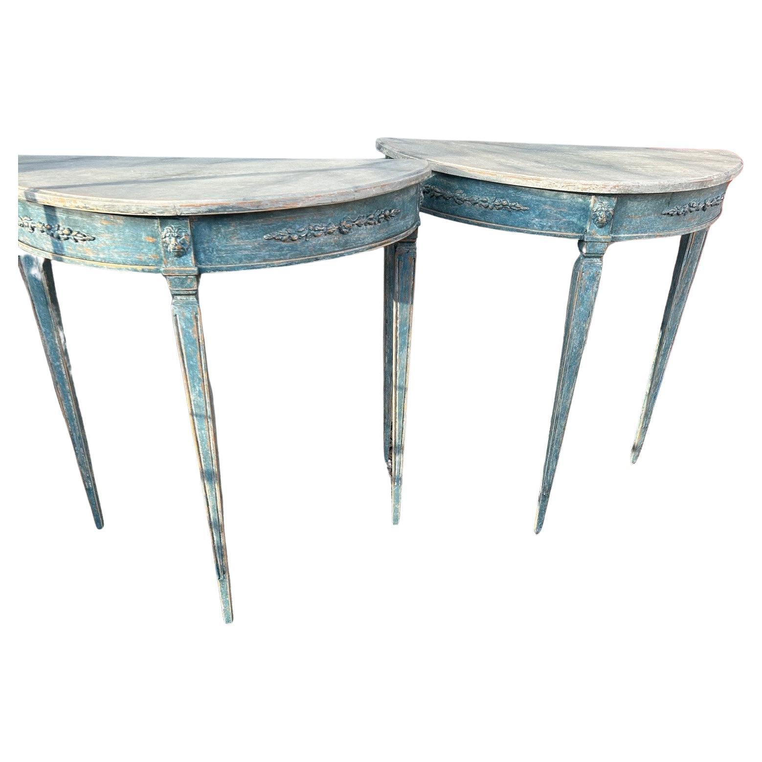 Pair of Demilune console tables in Gustavian style.

Gray marble painted tabletop with profiled edge.
Blue-painted base with curved apron. Tapered legs with fluting.

Sold as a pair.