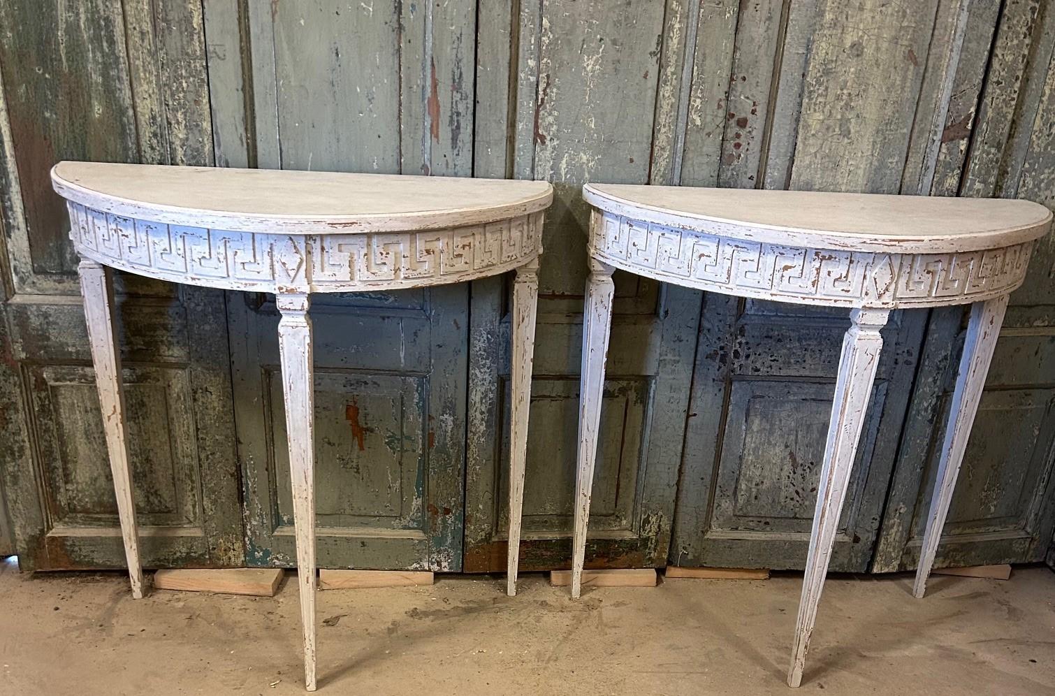 Pair of demilune console tables in Gustavian style.
Tabletop with profiled edge. Base with curved apron featuring carved à la grecque border and diamonds. Tapered legs with fluting.

Sweden, circa 1900.
Sold as a pair.