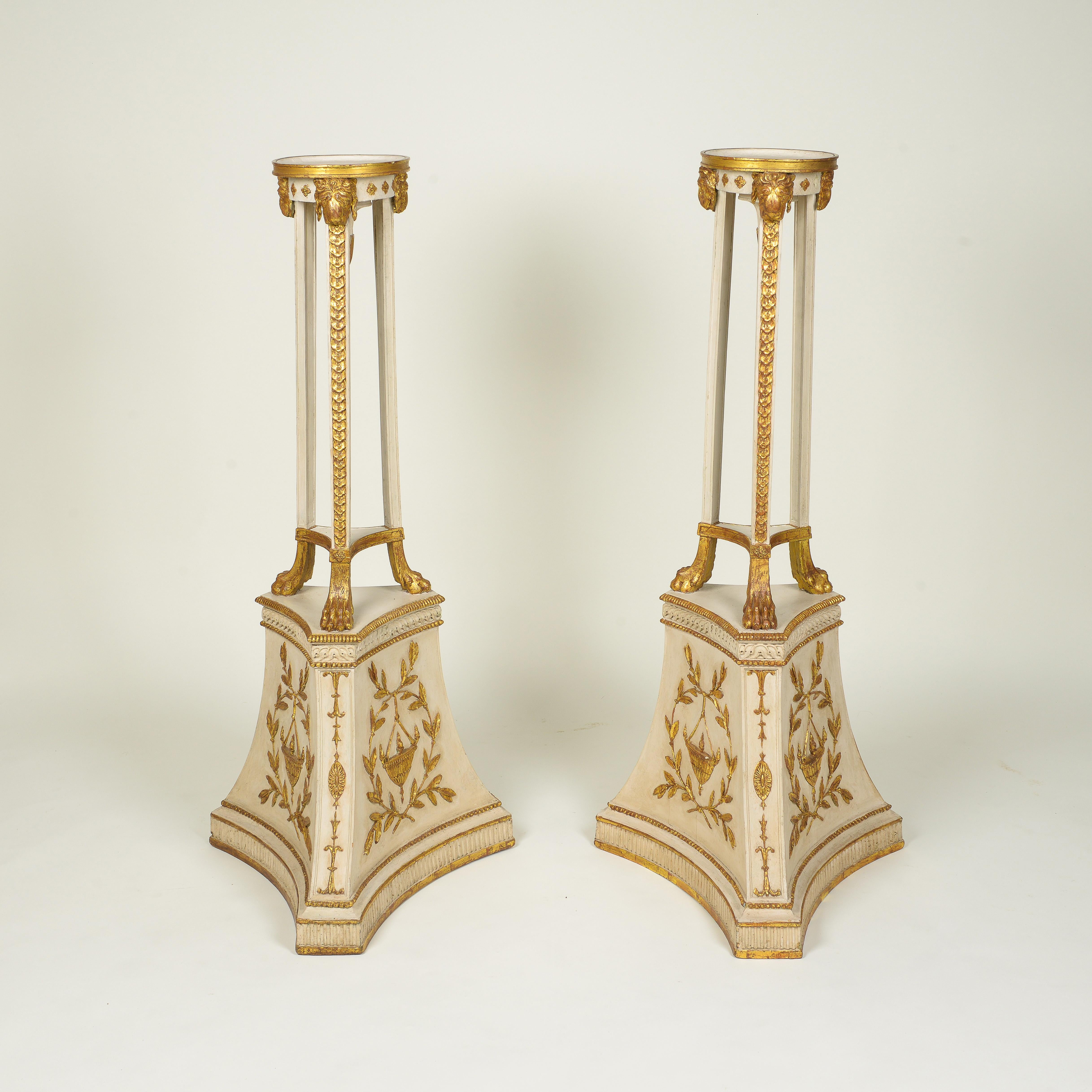 Each with round gilt-edged platform supported on three square legs with guilloche decoration, headed by lion's masks and terminating in paw feet; on a tripartite spreading base with gilt low-relief laurel wreaths encircling pendant urns; with
