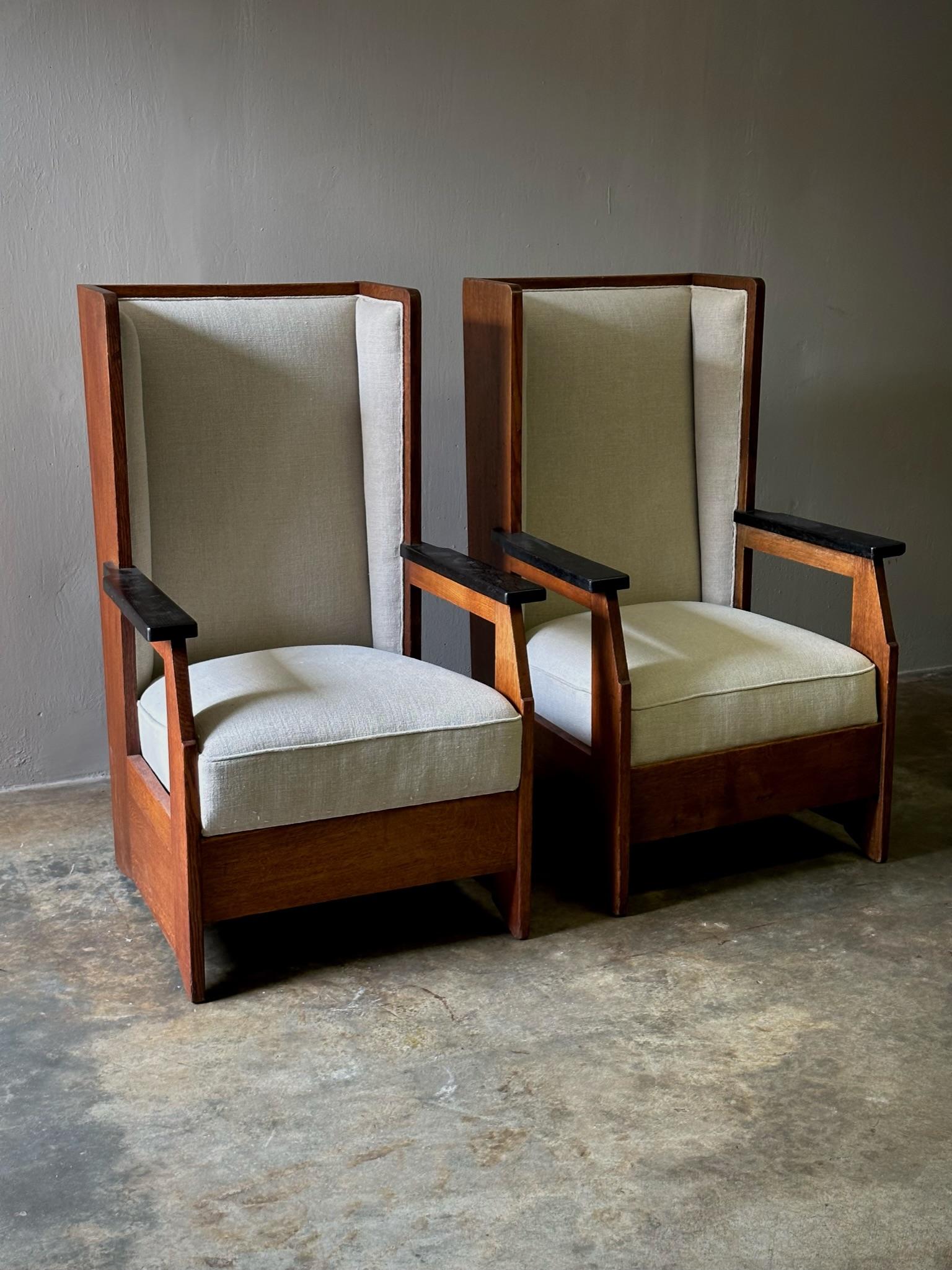Unique set of two 1920s Haagse School high back armchairs with white linen upholstery, designed by influential architect Hendrik Wouda for the firm H. Pander & Zonen. Dramatic and inviting, the pair is defined by their straightforward, well-balanced