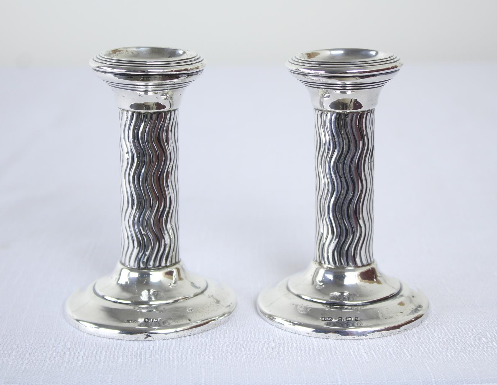A pair of Arts & Crafts silver candlesticks on circular stepped bases with short rounds columns with wavy line decoration and flared tops. Made by Henry Clifford Davies, Birmingham, 1908. Hallmarked on bases. In good original condition.