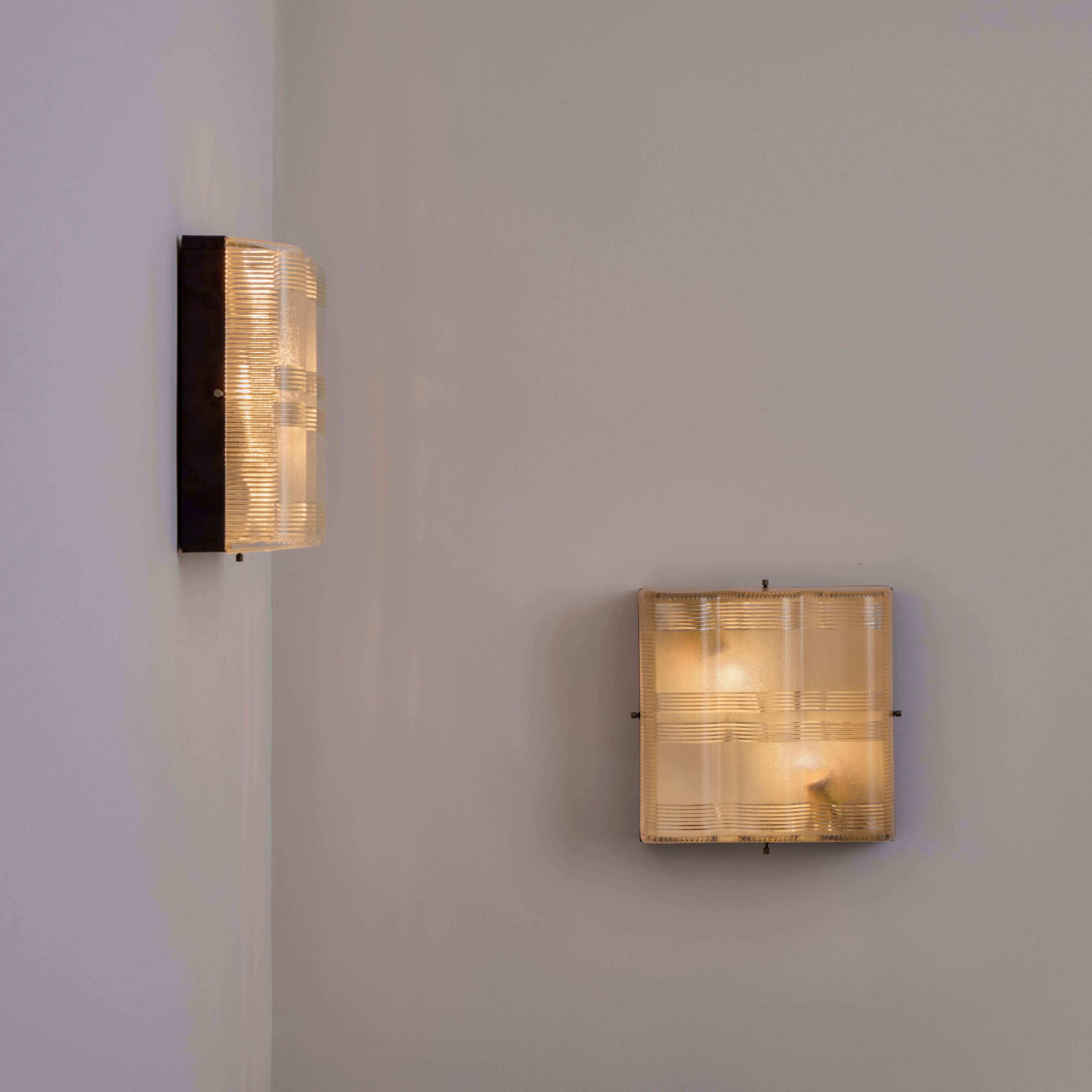 Pair of Halophane Sconces. Designed and manufactured in Italy, circa the 1950s. Halophane glass and enameled metal make up these versatile sconce. The glass diffusers feature a curved surface and a trio of glass textures, delivering a striking