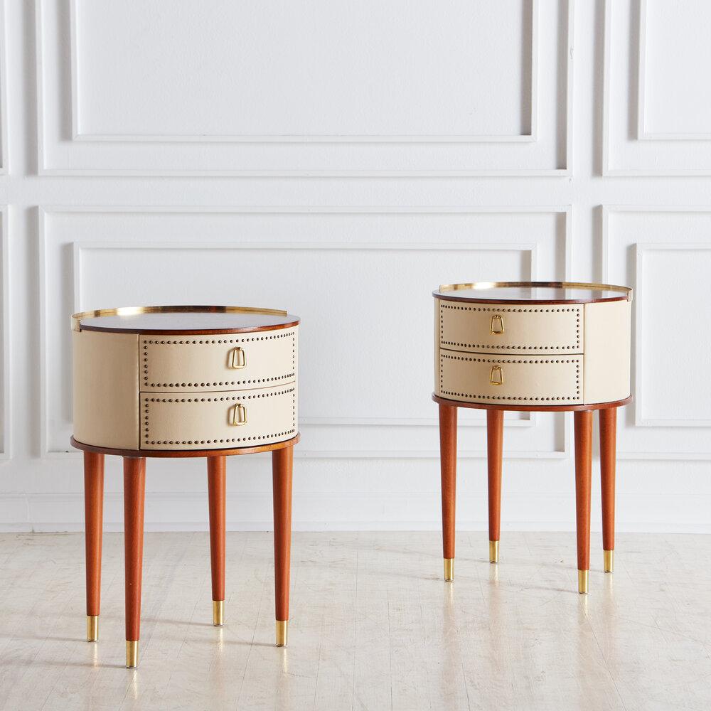 A pair of rare Swedish mid-century round nightstands designed by Halvdan Pettersson for Tibro Möbelfabrik, 1940’s. Mahogany tabletop with cream faux leather and tall tapered stained beech legs. Featuring a delicate brass detailing and two drawers.