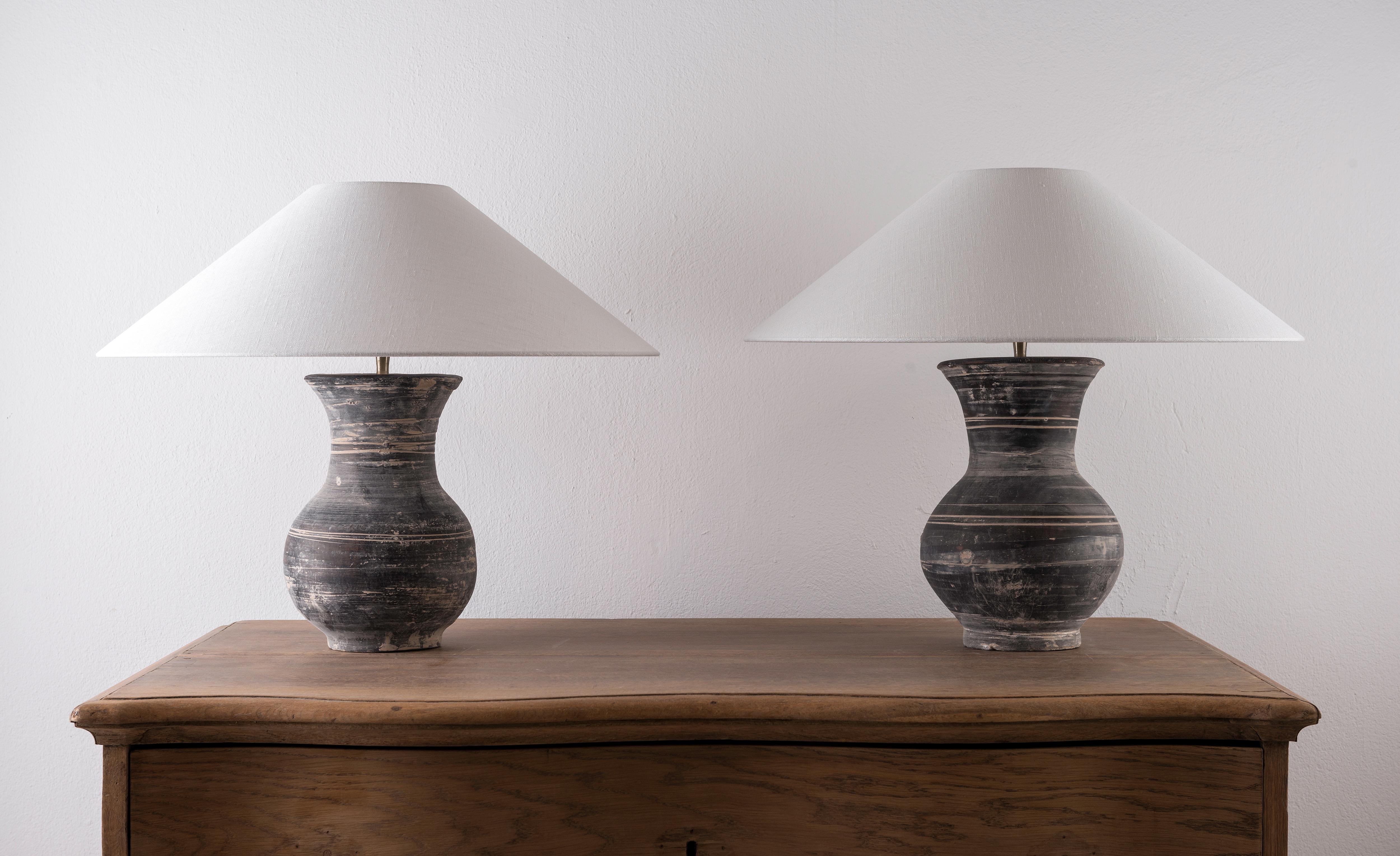 A beautiful pair of unglazed Han dynasty style vases of a very elegant form.
Expectedly mounted as lamps. High quality mount with a brass adjustable pivot joint. Shade handmade in Belgium.
The vases are from Zhejiang, china, mount and shade are
