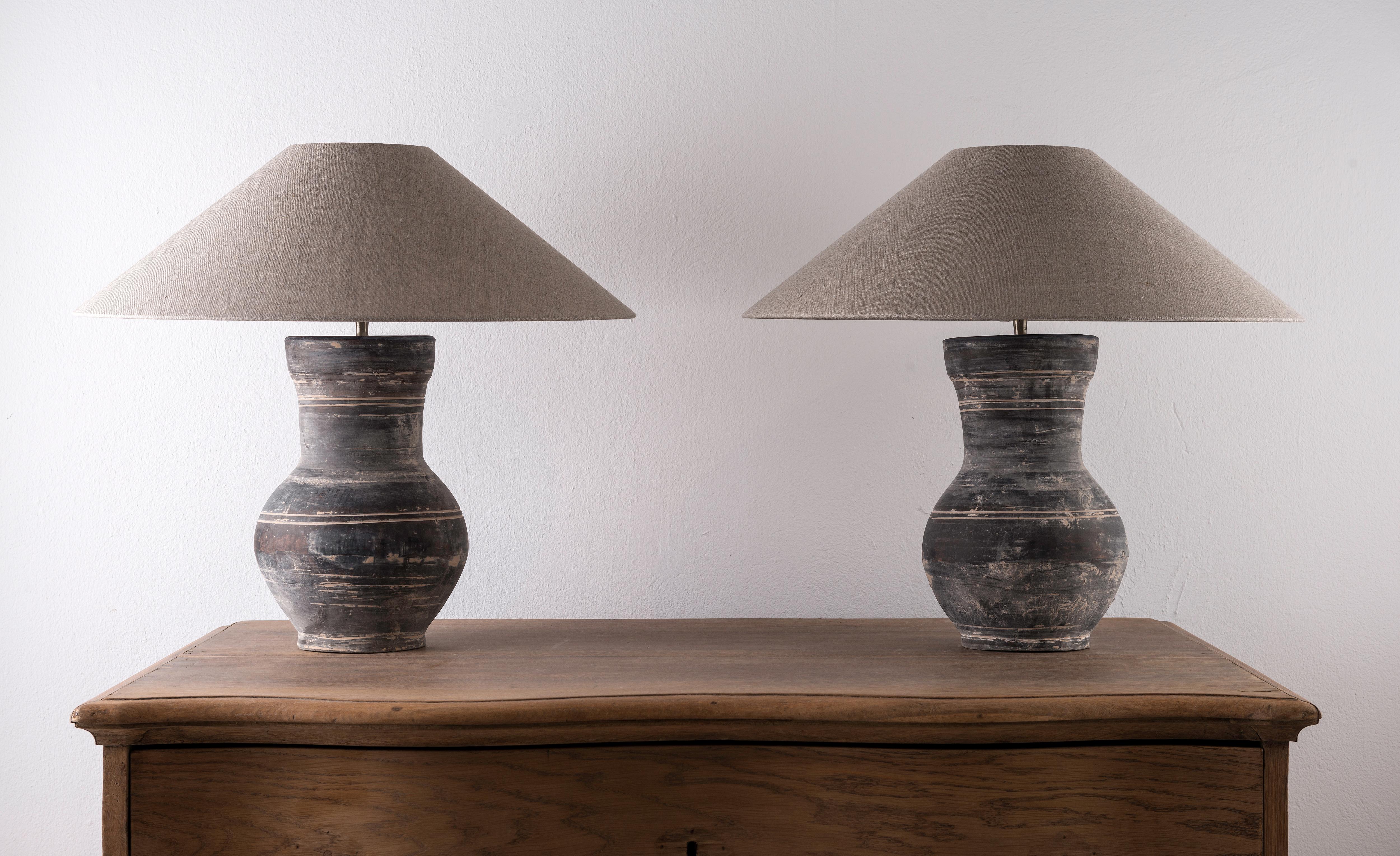 A beautiful pair of unglazed Han dynasty style vases of a very elegant form.
Expectedly mounted as lamps. High quality mount with a brass adjustable pivot joint. Shade handmade in Belgium.
The vases are from Zhejiang, china, mount and shade are made