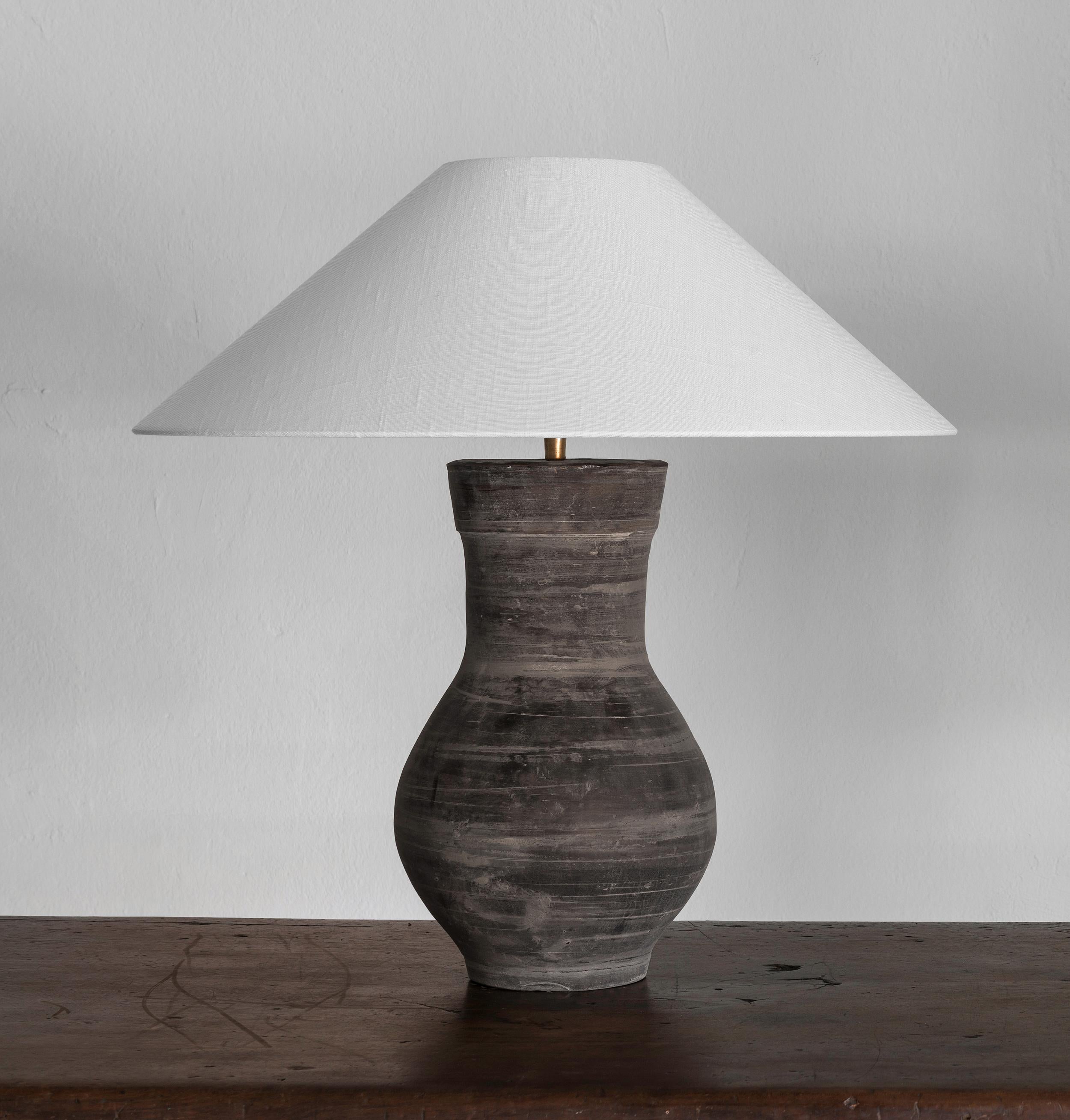One beautiful unglazed Han dynasty style vase of a very elegant form.
Expectedly mounted as lamp. High quality mount with a brass adjustable pivot joint. Shade handmade in Belgium.
The vase is from Zhejiang, china, mount and shade are made in