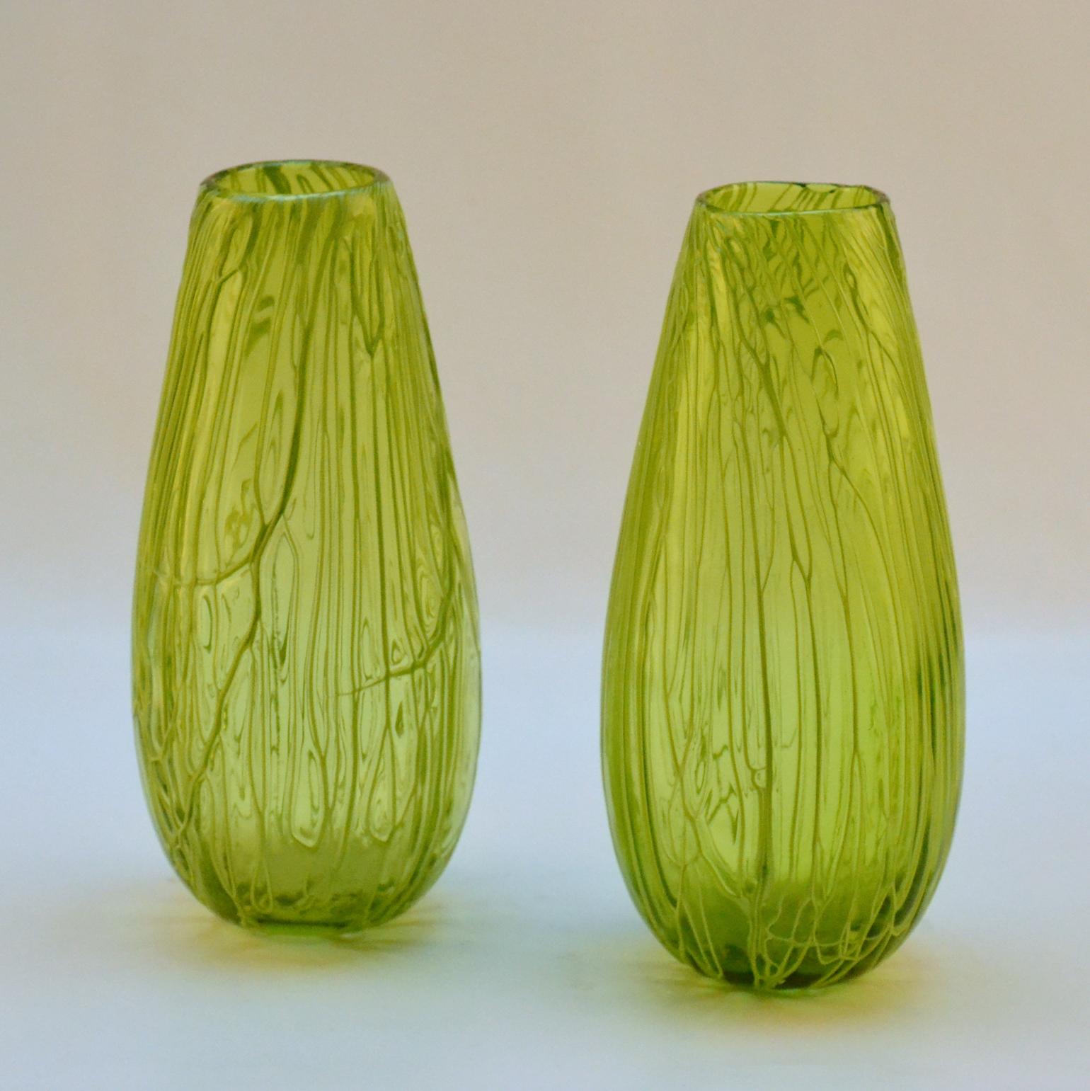 Cette paire de vases d'un vert acide vif a été réalisée à l'aide de la technique du Caldo, souvent utilisée à Murano, qui consiste à faire courir des fils de spaghetti sur la surface, sur le corps, pour créer ce relief texturé, pendant le processus