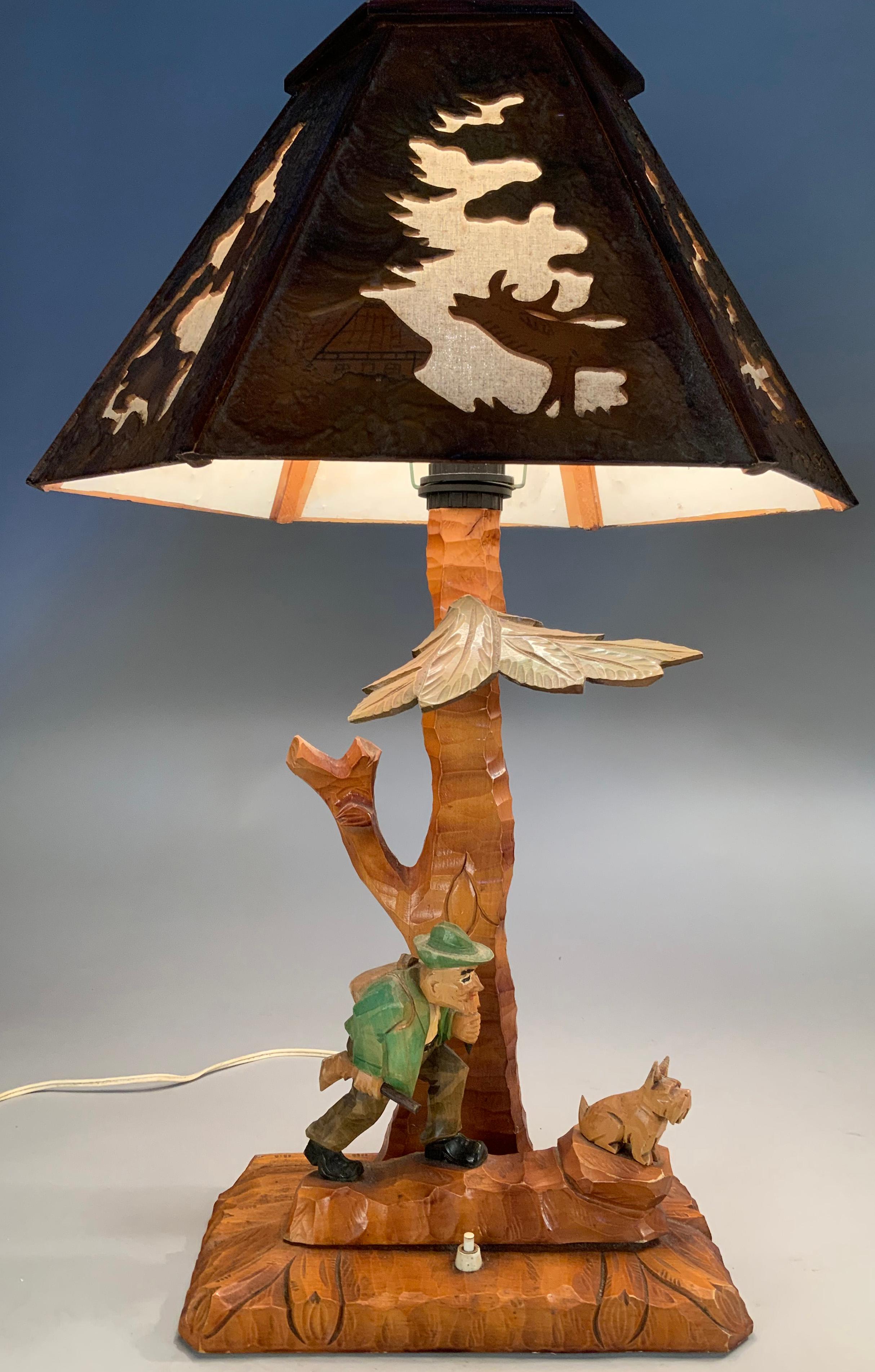 an incredibly charming pair of vintage 1970's hard carved Adirondack wood lamps, with charming bases having carved figures of a hunter and stag. both lamps have their original wood shades, carved and pierced, with canvas backing. wonderful details