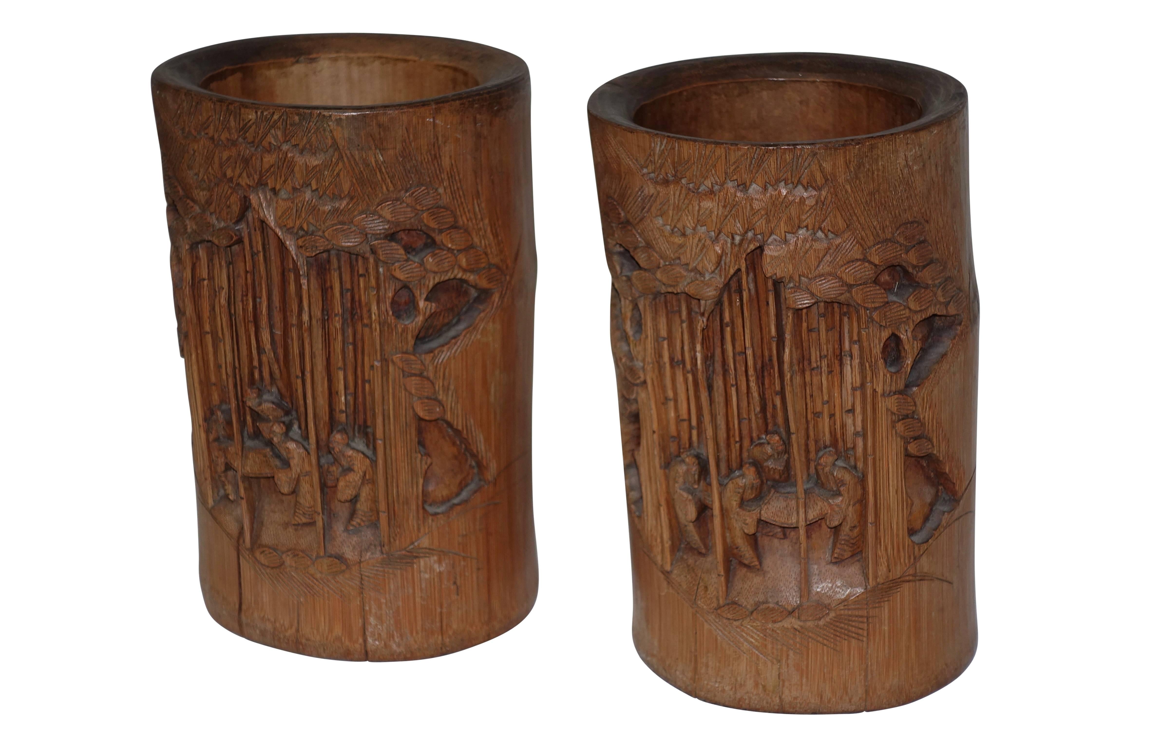 A unique pair of hand-carved brush pots with scenes of figures cultivating a grove of bamboo shoots. Japan, 19th century.