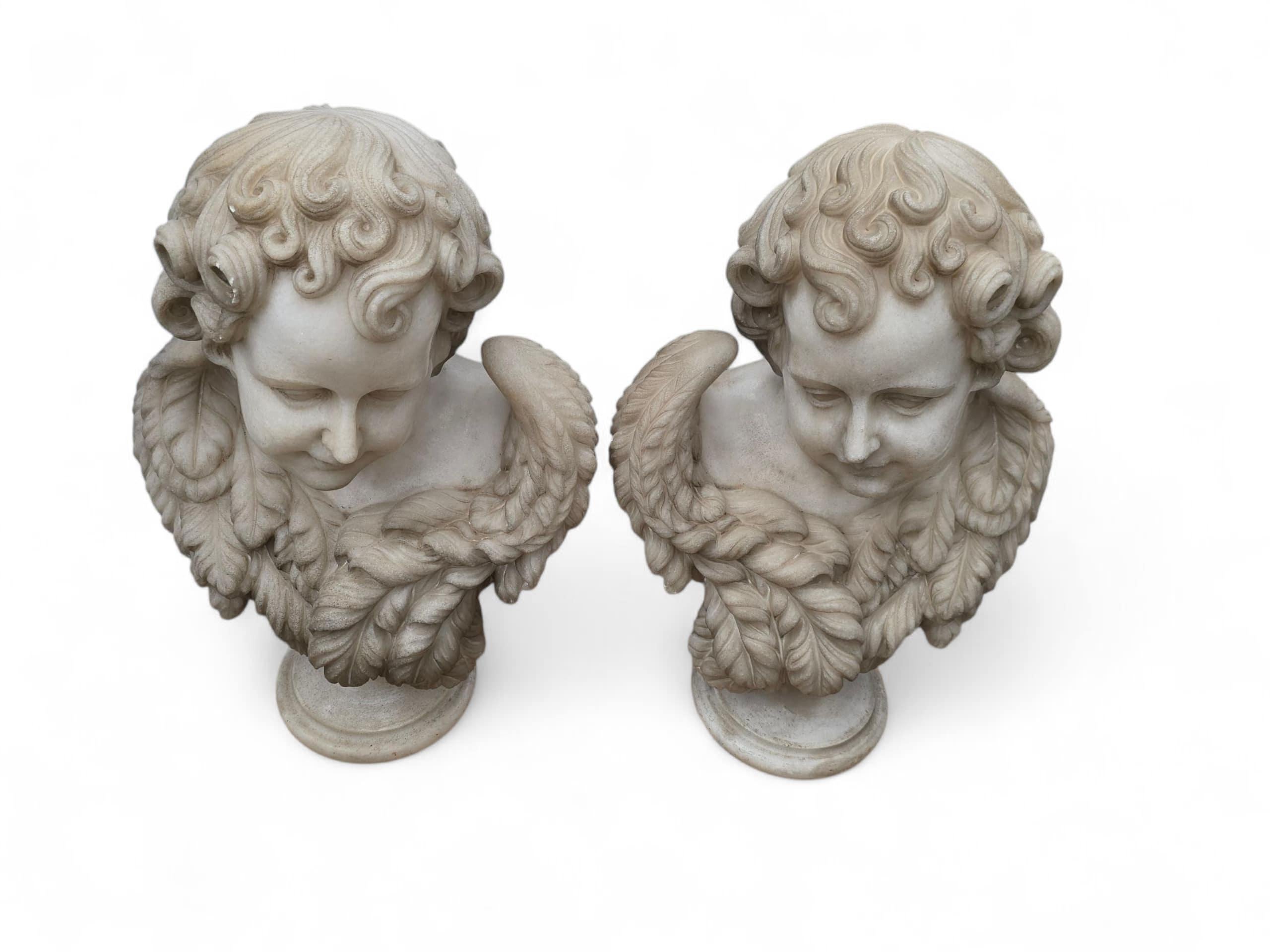 Elegant pair of marble busts depicting cherubs, finely hand-carved in white Carrara marble in Italy during the 20th century. Each figure is sculpted with delicate features, curly hair, and serene expressions—capturing the innocence and charm typical
